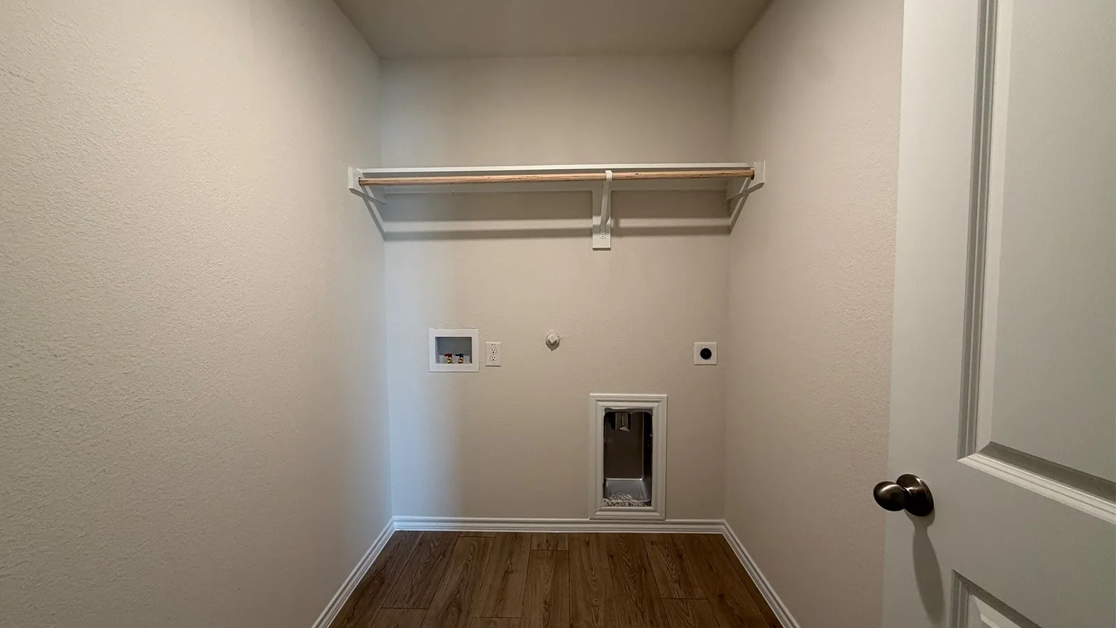 Dedicated utility room featuring wood-finish flooring, light neutral walls, and a white baseboard trim