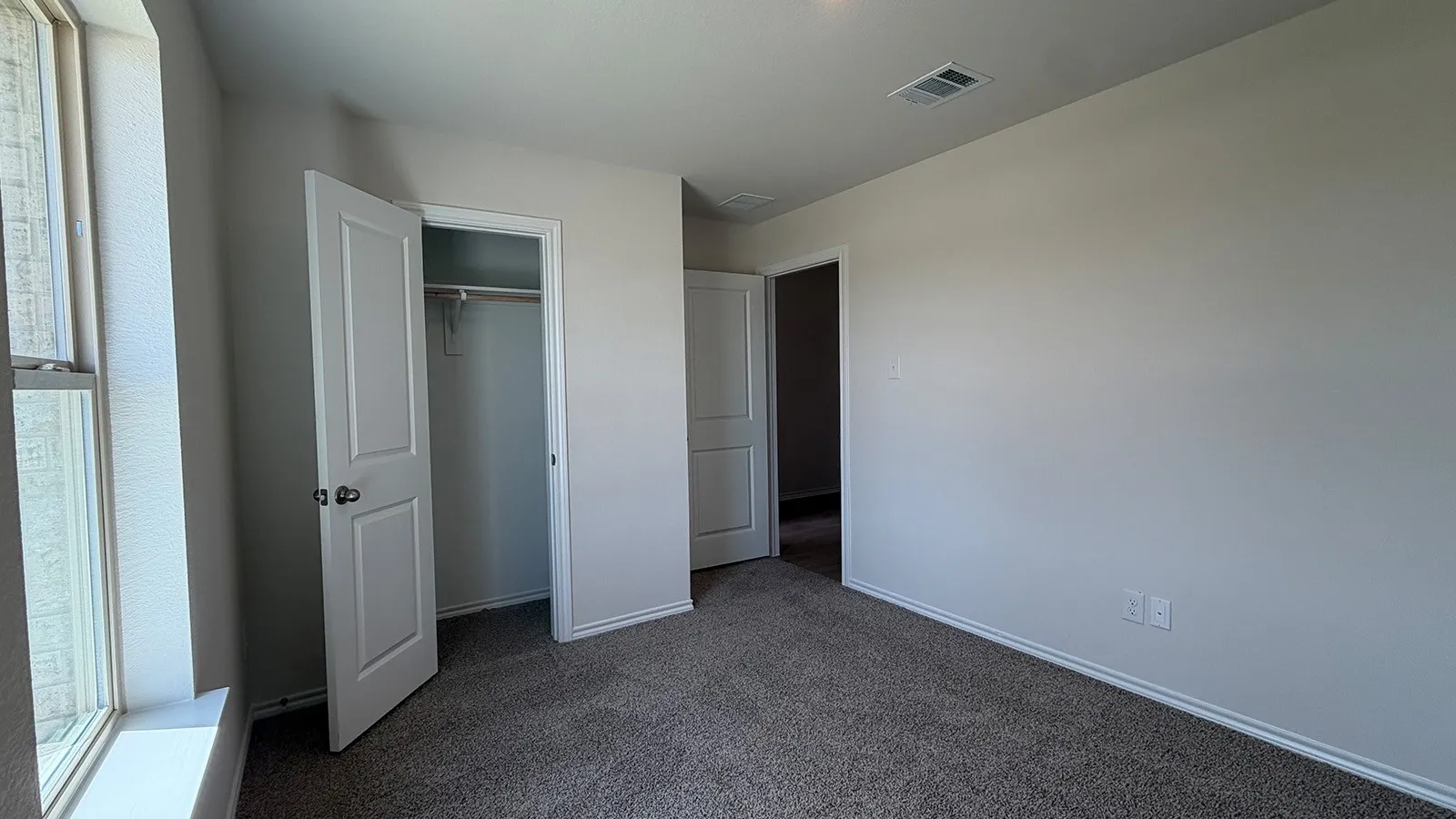 Carpeted room with a double-pane window, white trim, and light gray walls