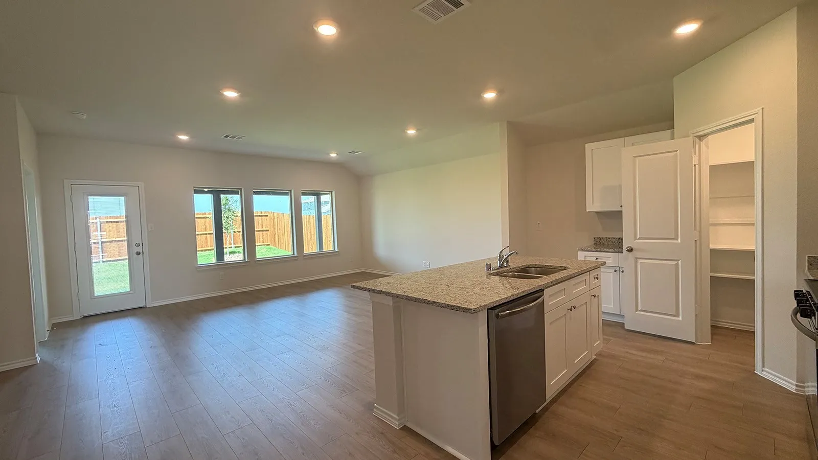 Open-concept living area featuring wood-finish flooring, recessed lighting, and multiple windows