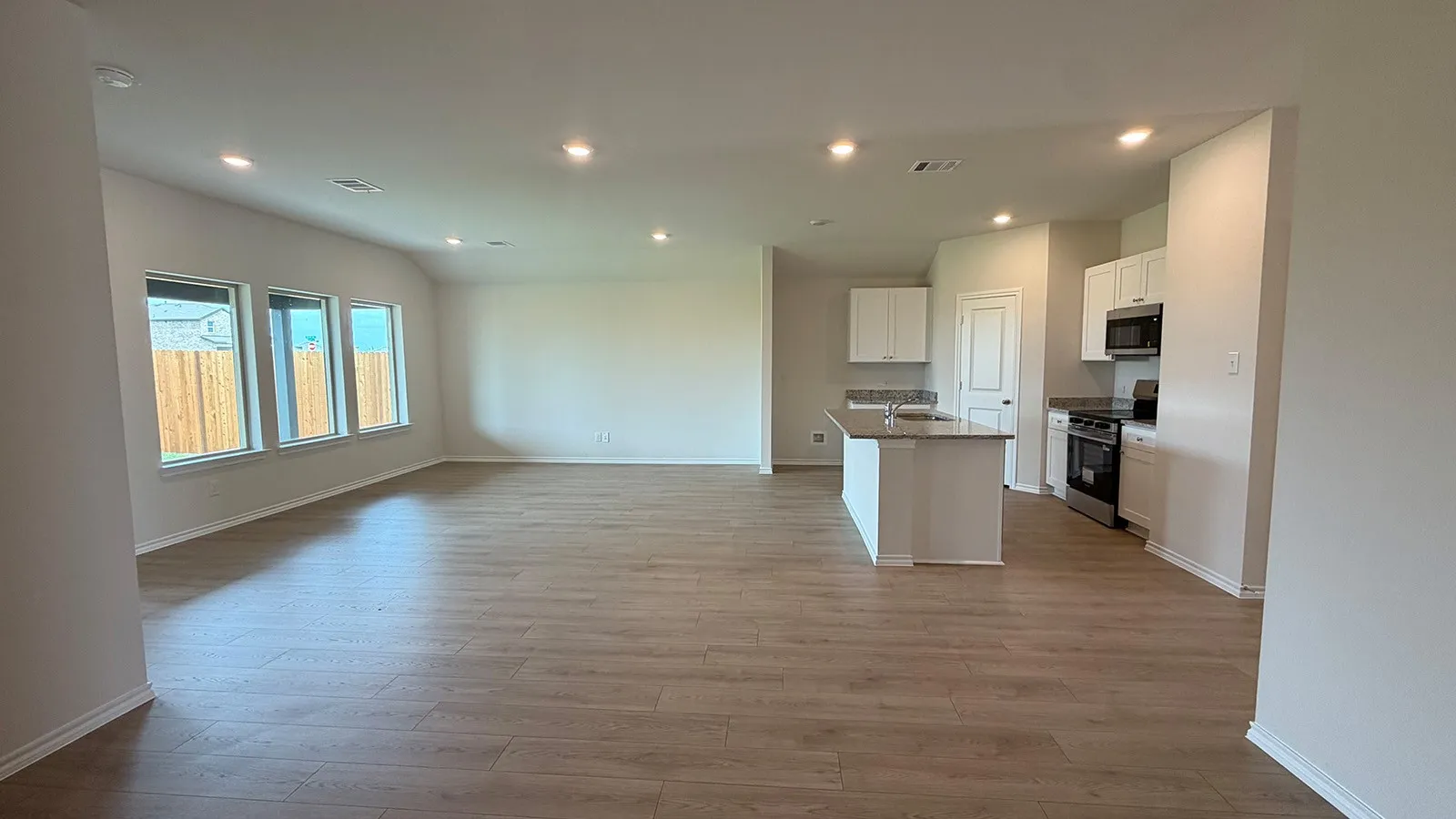 Open-concept living space featuring wood-finish flooring, recessed lighting, and multiple windows
