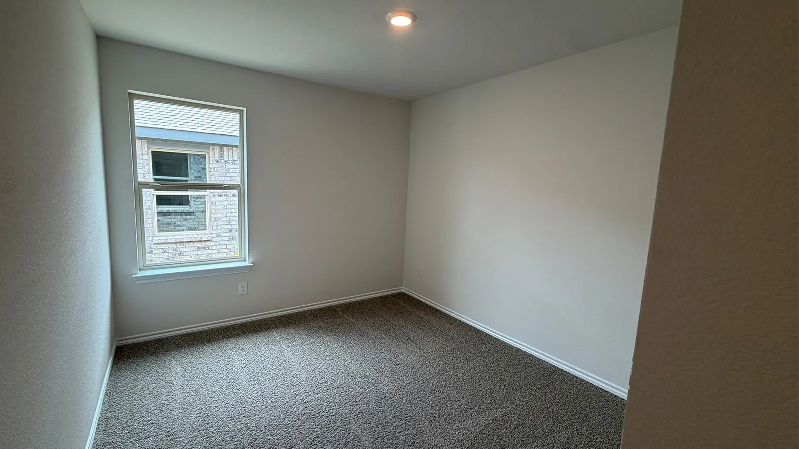 Neutral-toned room featuring a double-hung window, white trim, light-colored walls, recessed lighting, and textured carpeting