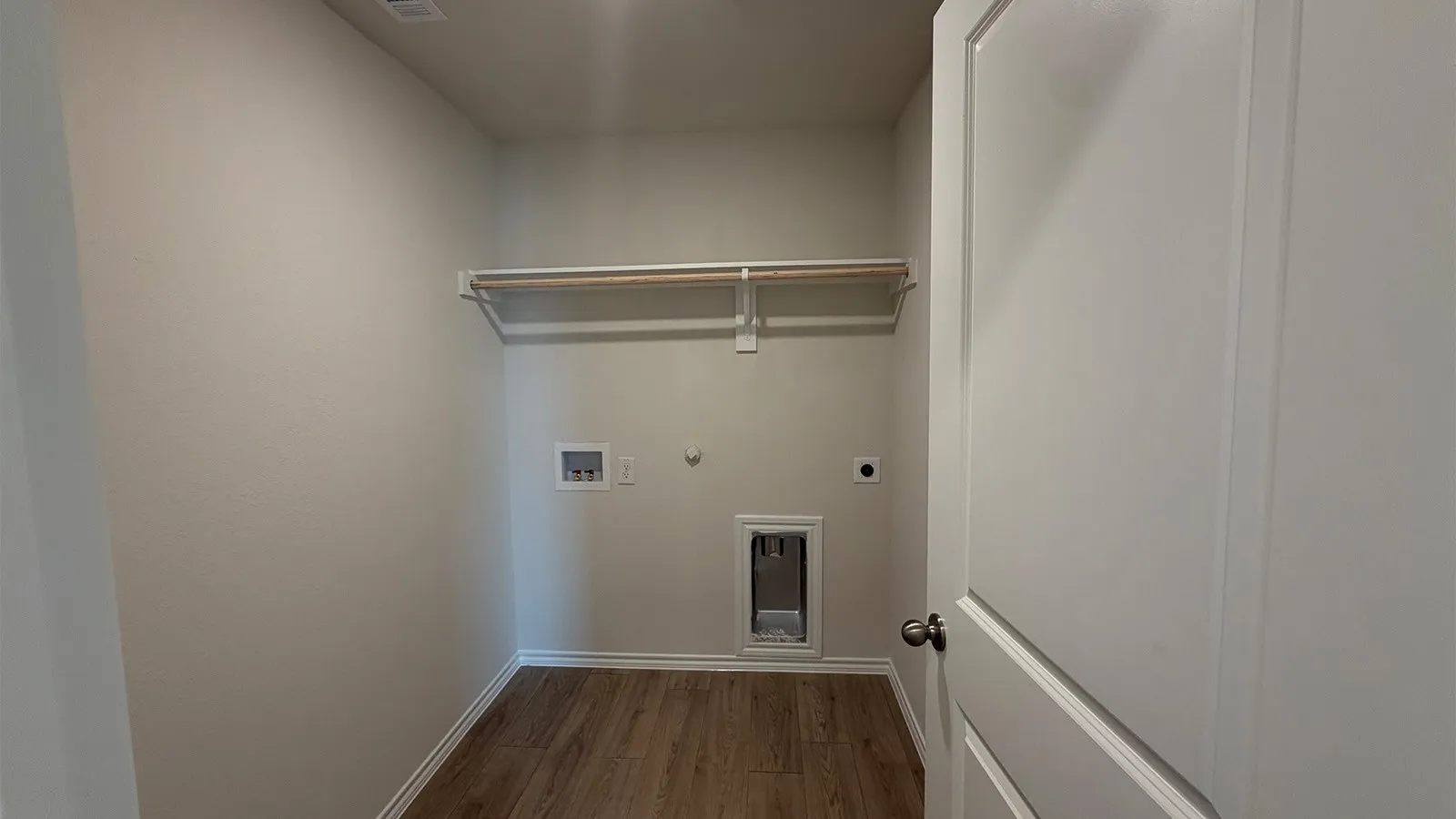 Dedicated utility space featuring wood-finish flooring, light neutral wall tones, and a built-in hanging rod