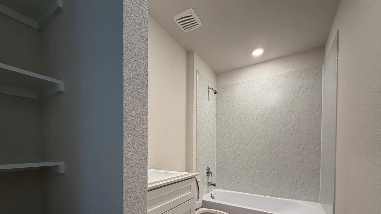 Bathroom featuring a white bathtub, patterned shower surround, and a chrome shower fixture