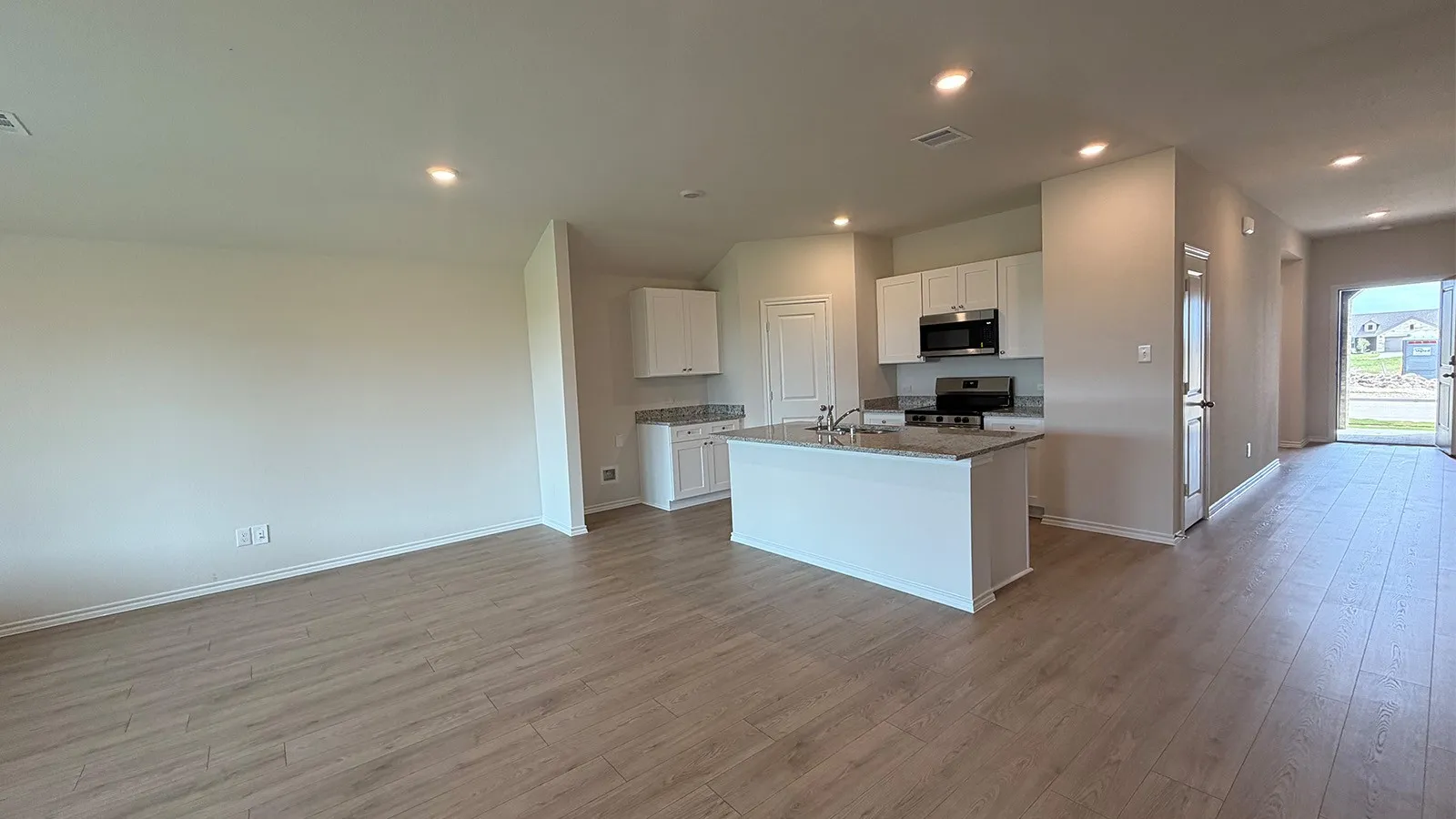 Open-concept living area featuring wood-finish flooring, recessed lighting, and a kitchen island with integrated sink