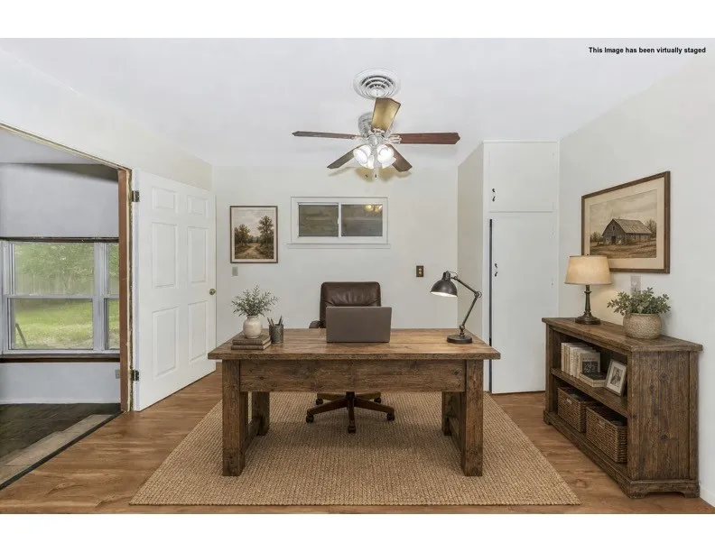 Interior room featuring wood-finish flooring, a ceiling fan, a window, and a paneled door