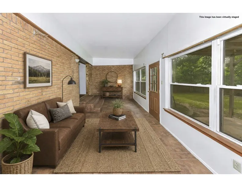 Bright interior space featuring a textured brick accent wall, extensive window detailing, and wood-finish flooring