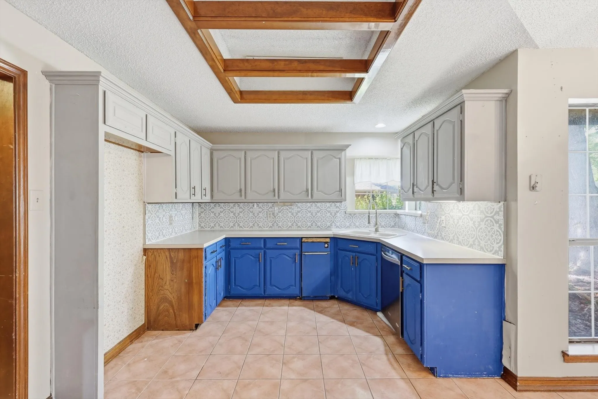 Kitchen with two-tone cabinetry, white countertops, and a patterned tile backsplash