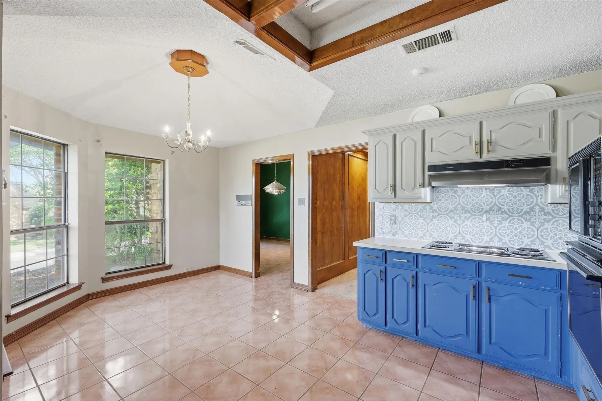 Kitchen featuring a white countertop, blue lower cabinetry, light gray upper cabinetry, and a patterned tile backsplash
