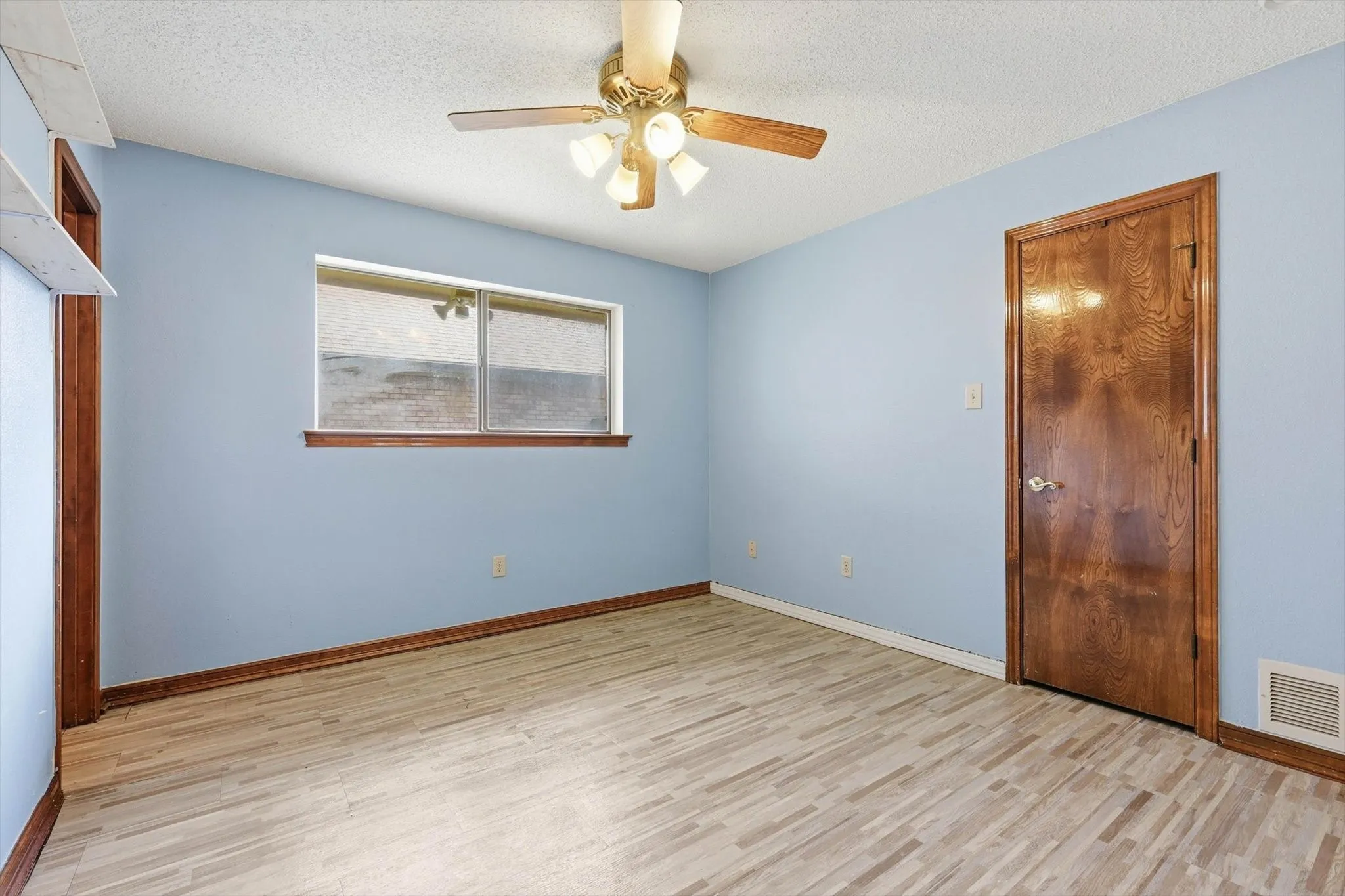 Room featuring wood-finish flooring, a ceiling fan with integrated lighting, and a single window with a wooden sill