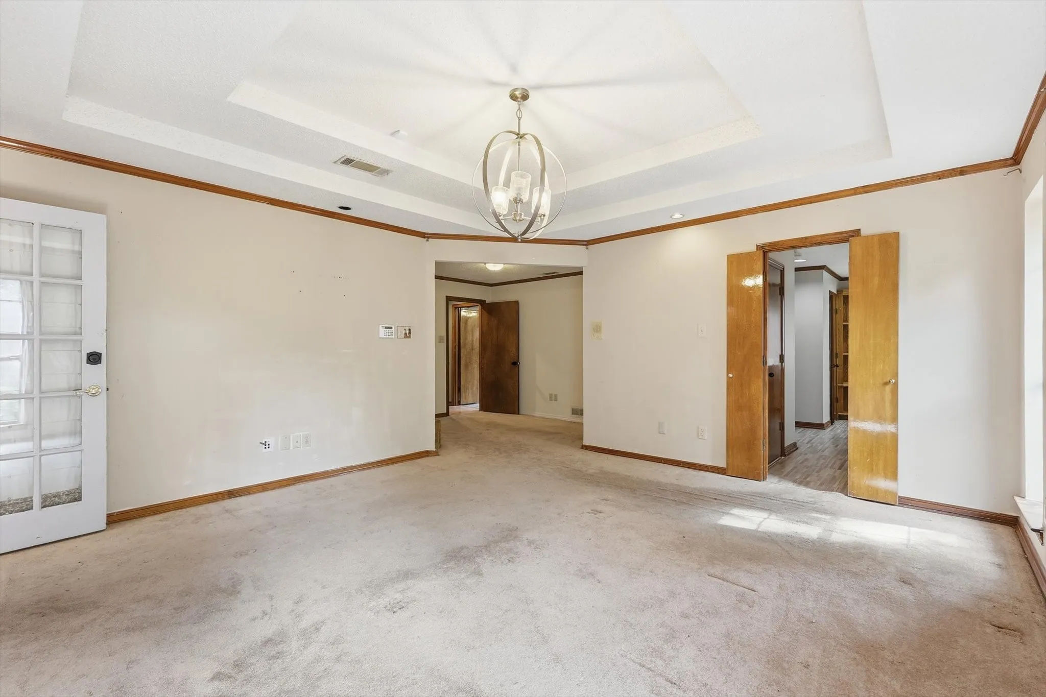 Spacious room with a tray ceiling and an overhead chandelier