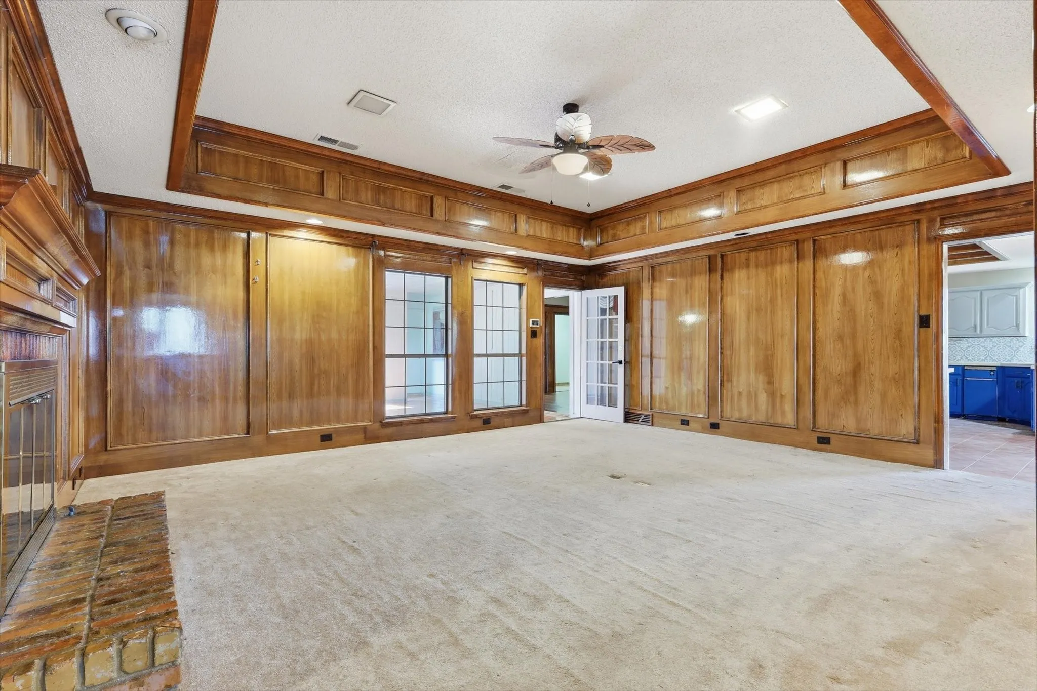 Spacious room featuring extensive wood paneling and trim, a coffered ceiling, and light-colored carpeting