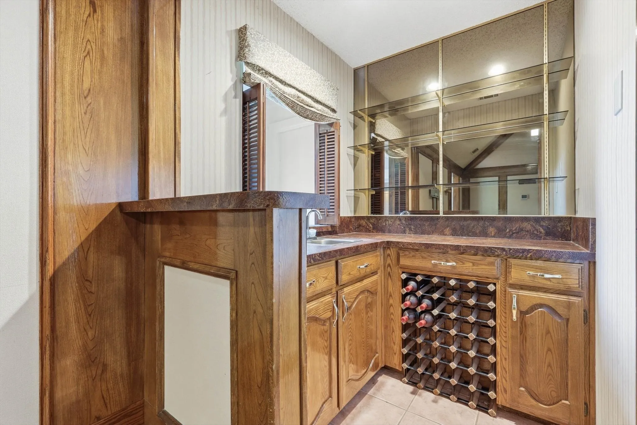 Built-in wet bar featuring wood cabinetry, stone-finish countertops, an integrated sink, and an extensive wine rack