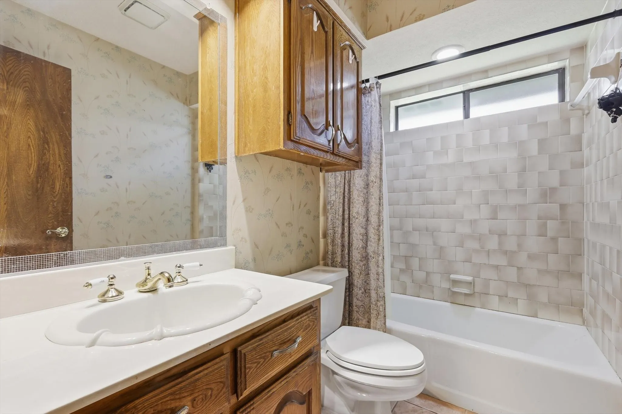 Bathroom featuring a white vanity with an undermount sink, brass-finish faucet, and wood-finish cabinetry