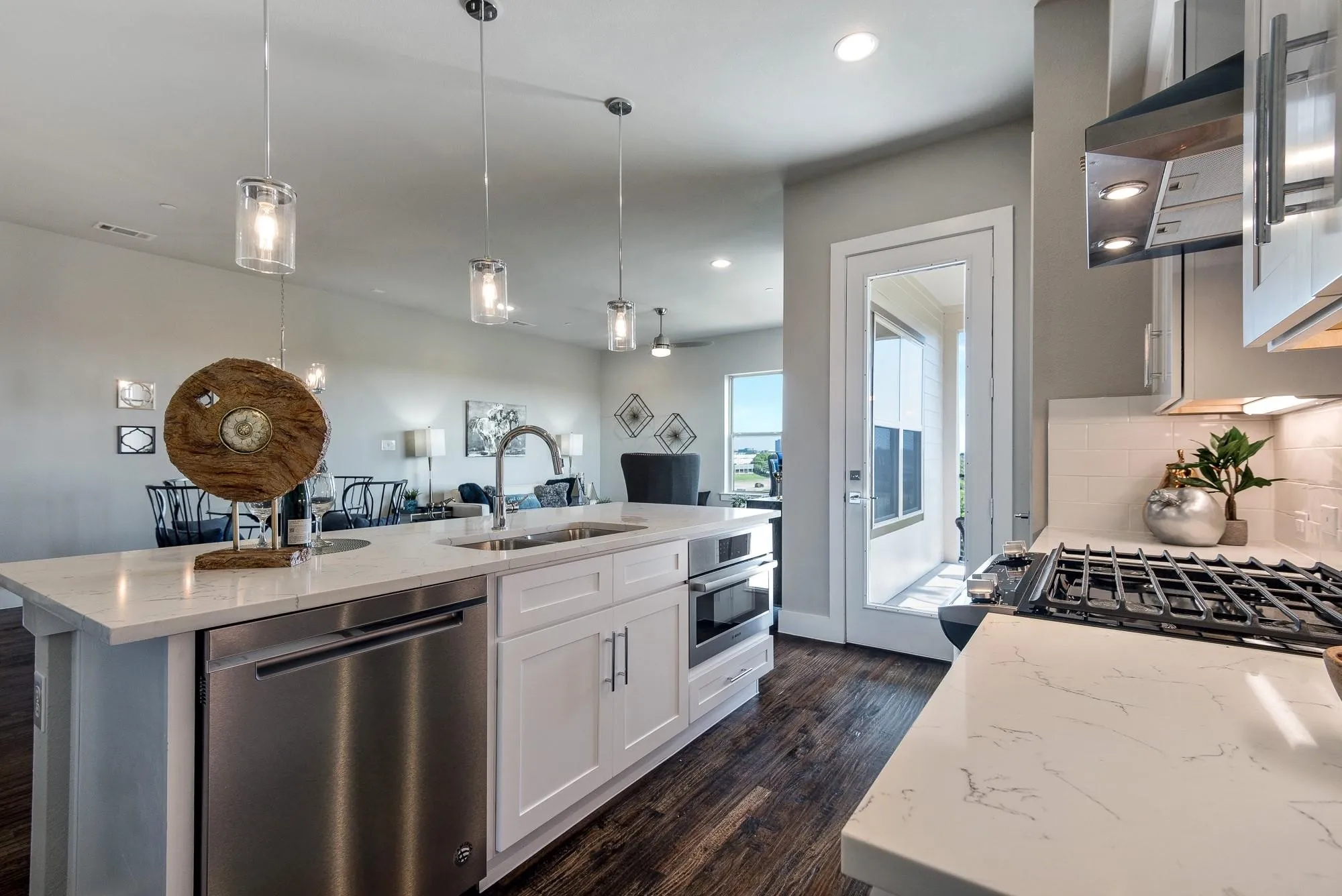Modern kitchen featuring white cabinetry, stainless steel appliances, a gas range, and a spacious island with a sink and pendant lighting