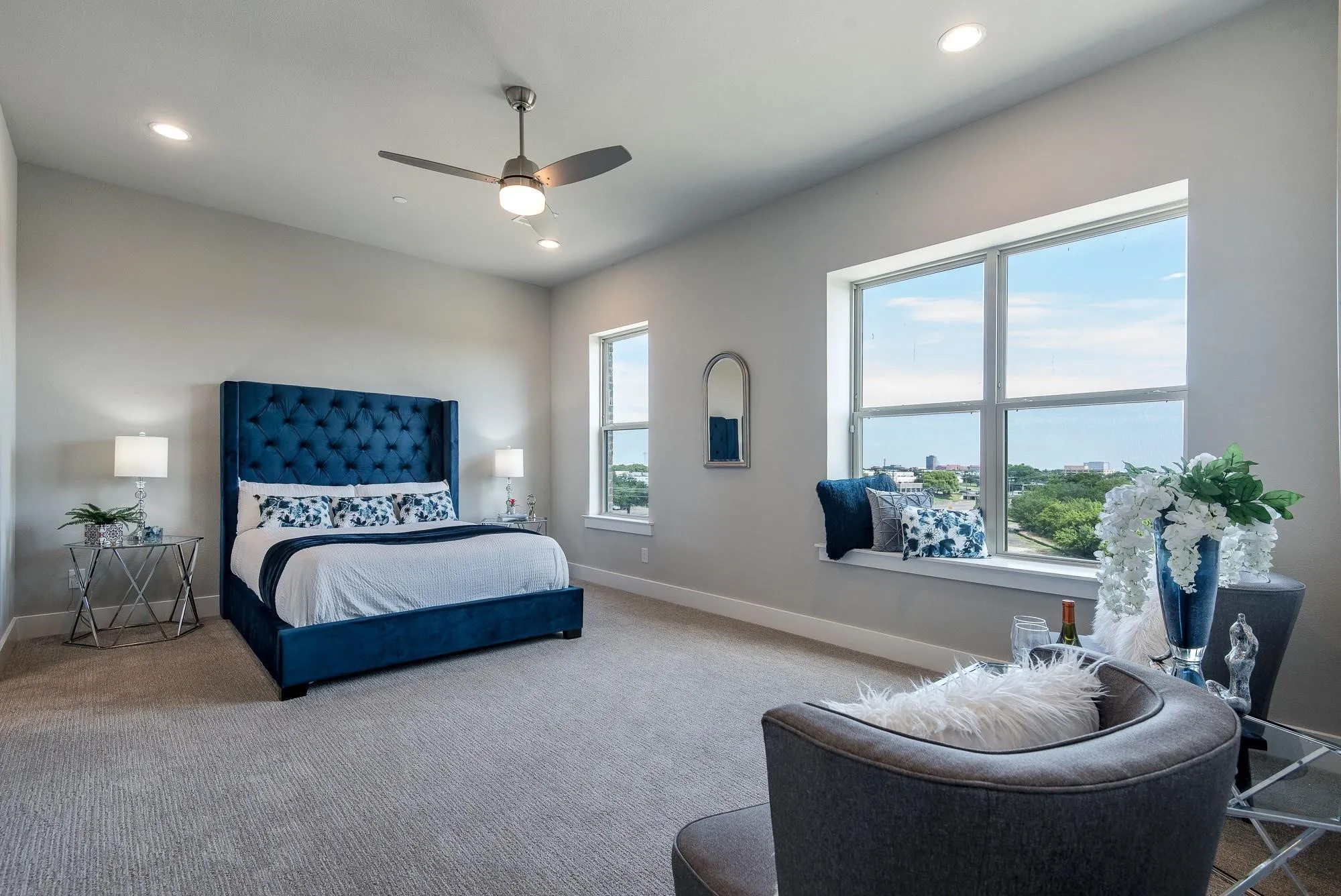 This spacious room features light gray walls, recessed lighting, and a ceiling fan