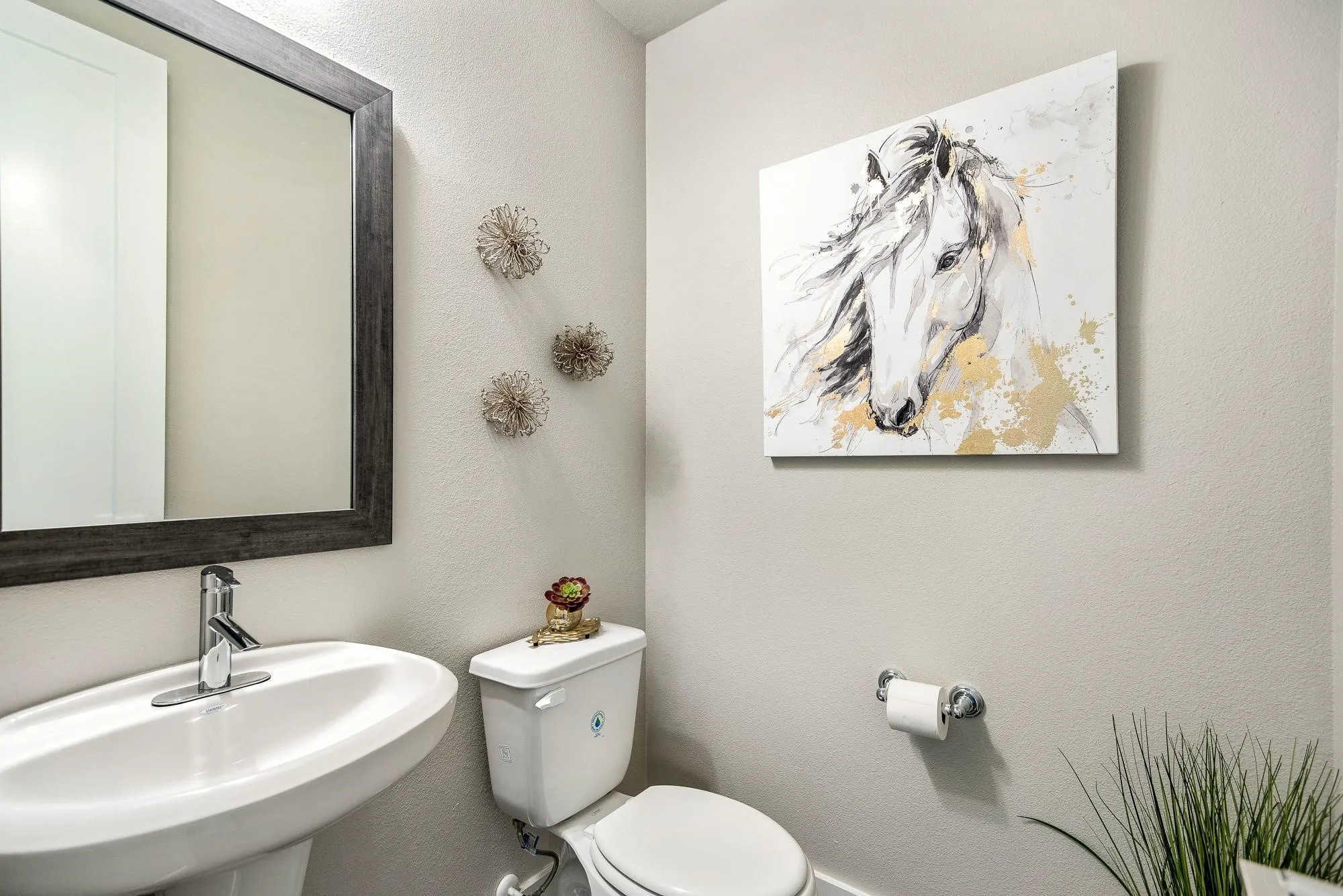 Powder room featuring a pedestal sink, a toilet, and a framed mirror