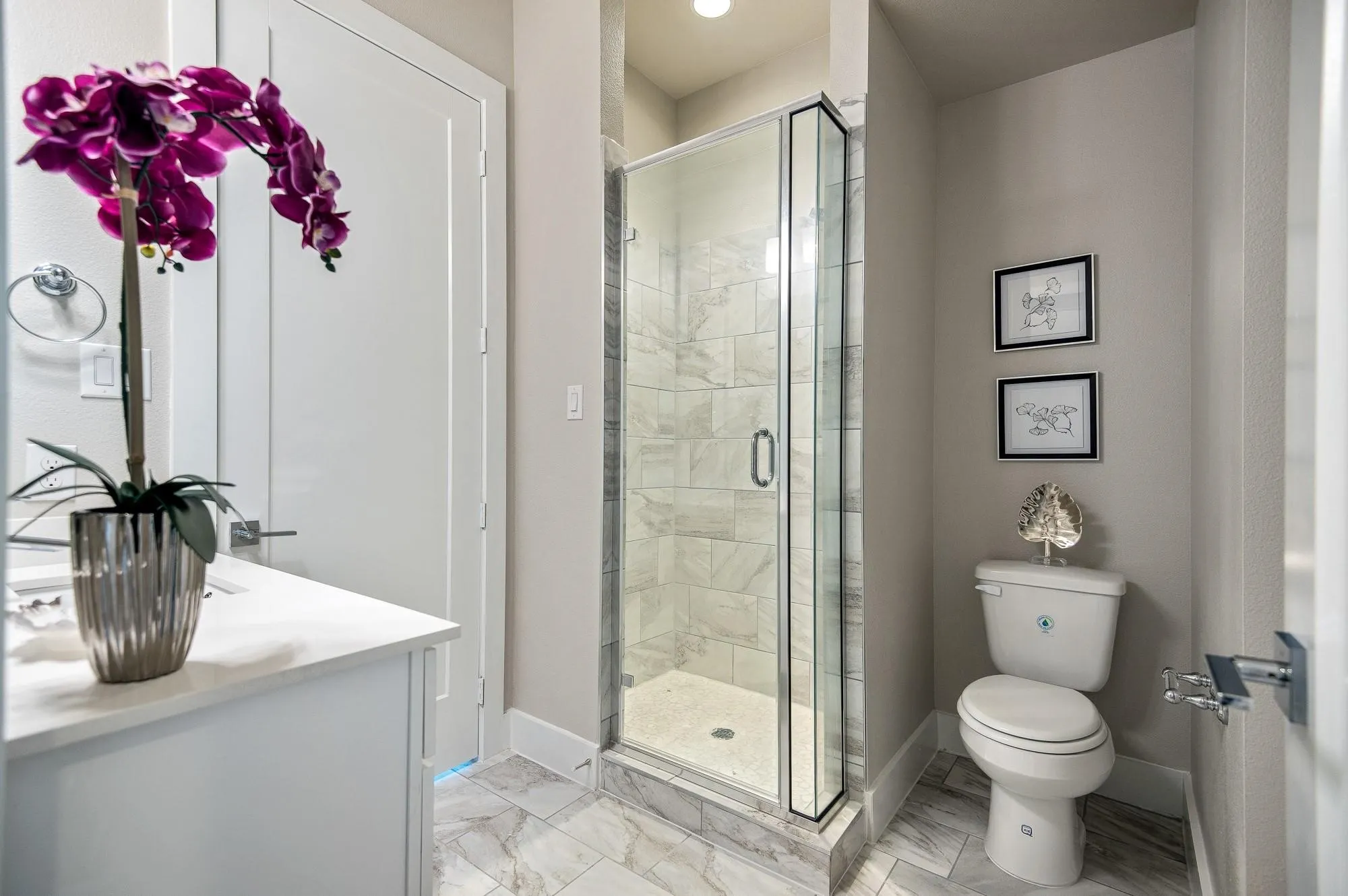 Bathroom featuring a glass-enclosed shower with tiled walls, a white vanity with a light-colored countertop, and a white toilet