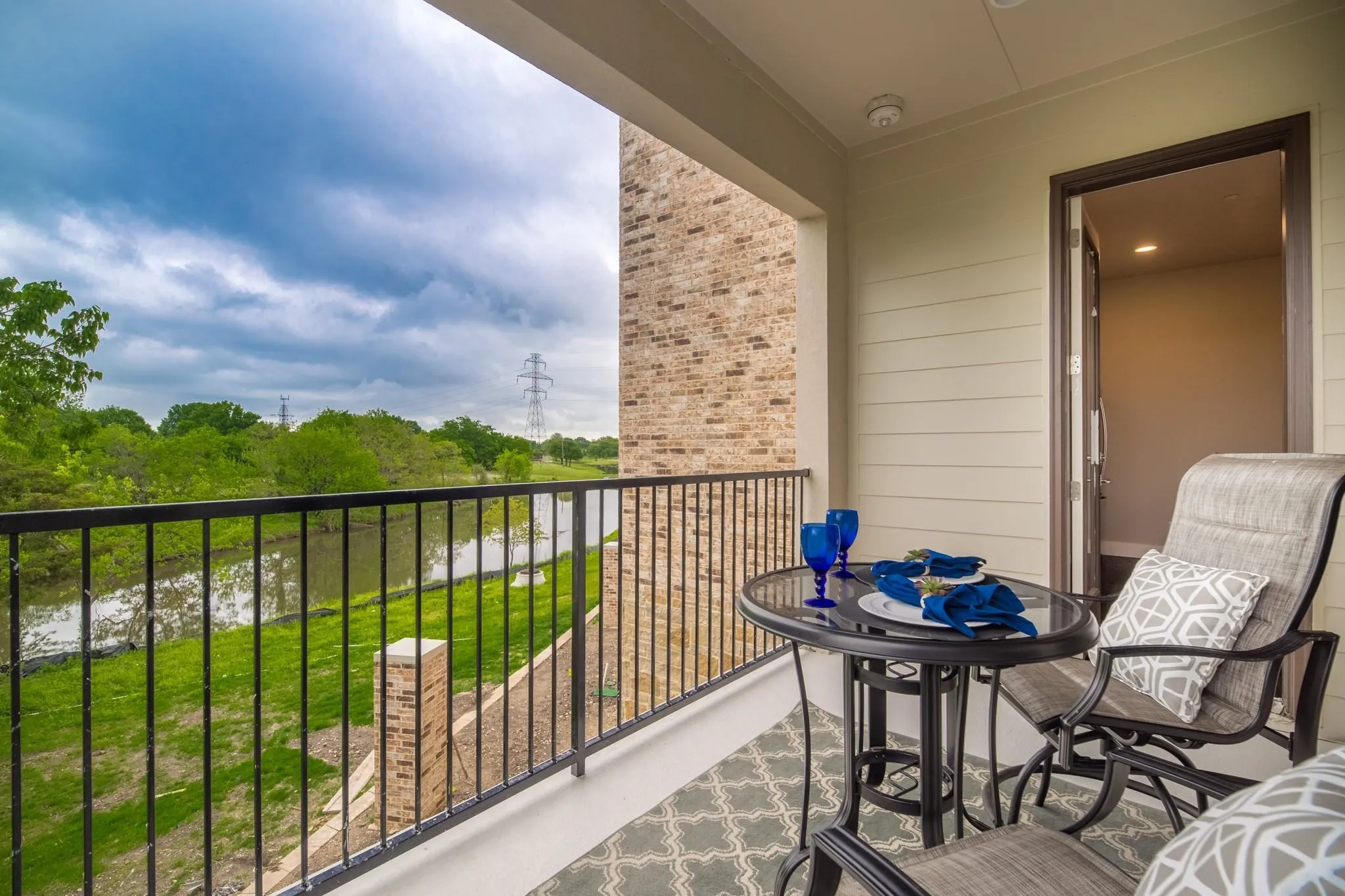 The property features a balcony with a wrought iron railing, offering a scenic view of a body of water and lush green foliage