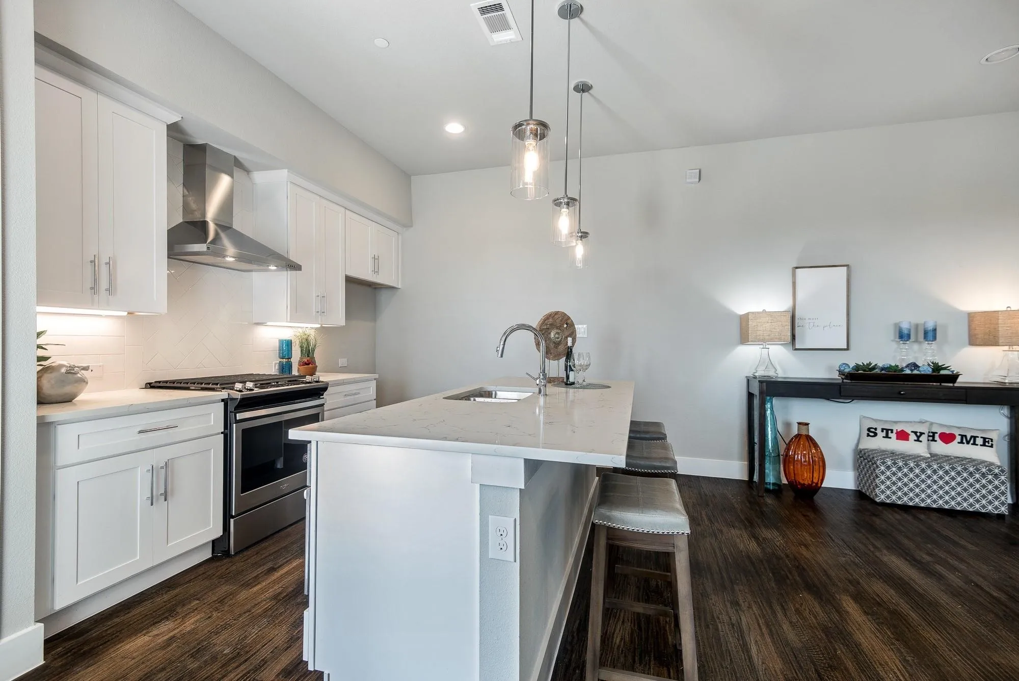 The property features a kitchen with white cabinetry, stainless steel appliances, and a central island with a sink and seating