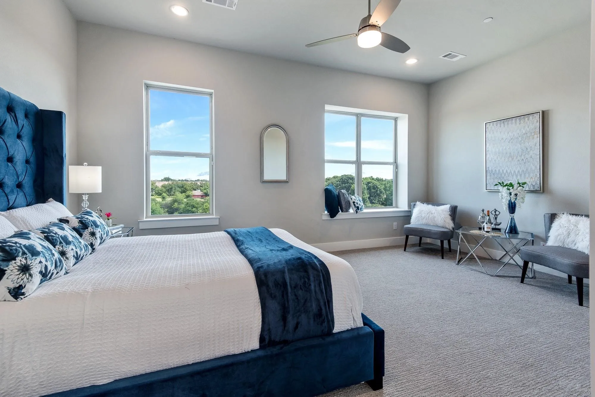 This room features two large windows, providing ample natural light and views of the surrounding trees and residential properties