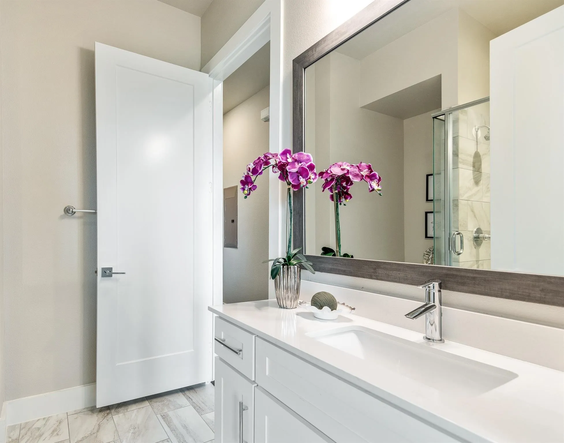 Bathroom featuring a vanity with a white countertop and an integrated sink, a large mirror with a wooden frame, and a shower with a clear glass enclosure