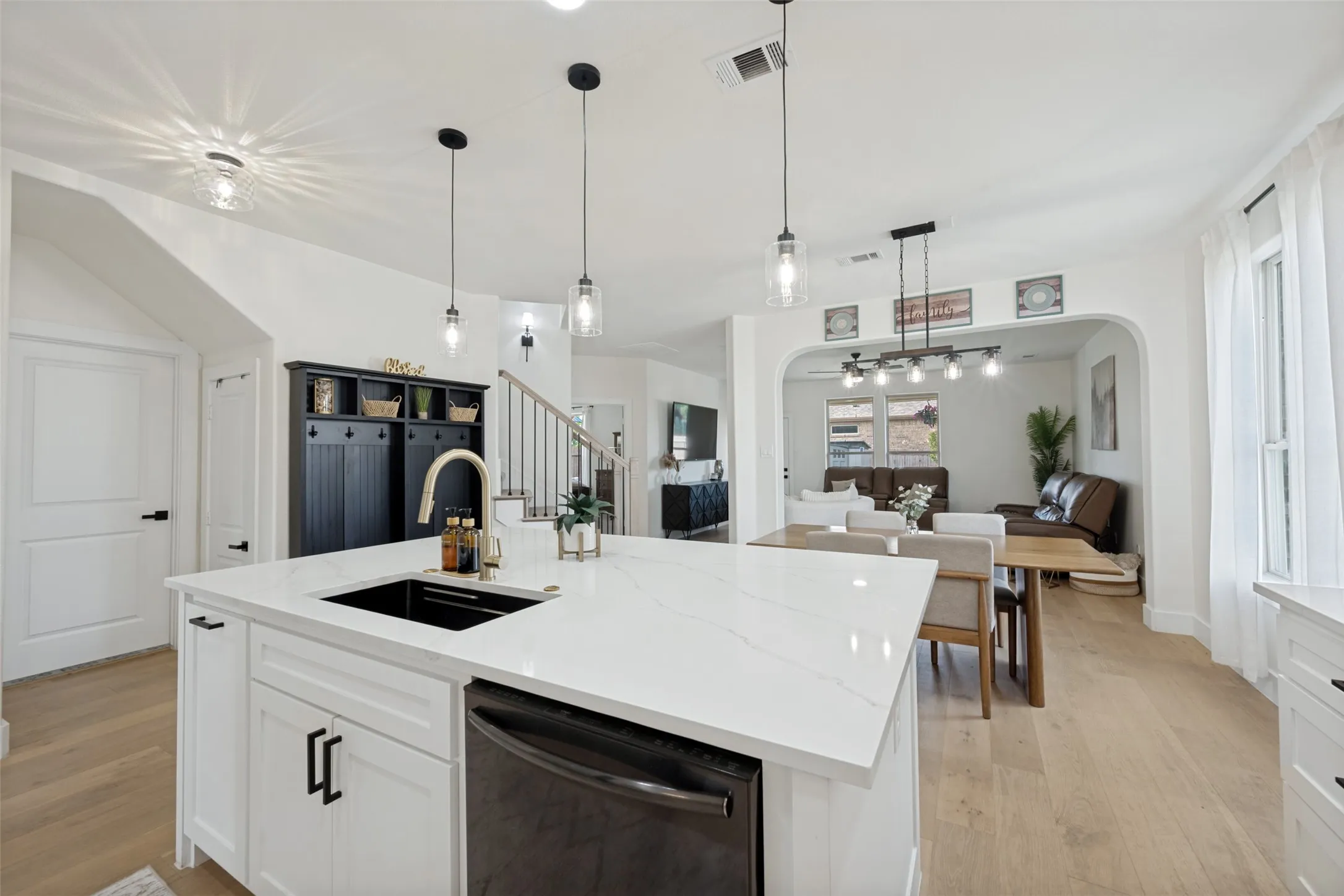 Kitchen island featuring a white countertop with subtle veining, undermount sink, and brass-finish faucet