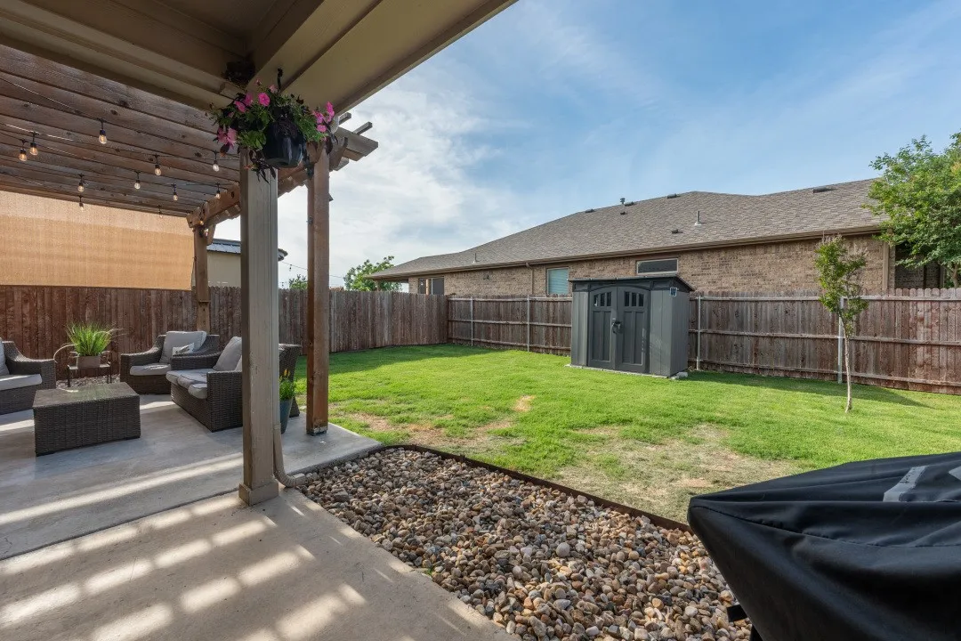 Covered patio featuring a wood pergola with string lighting and a privacy screen