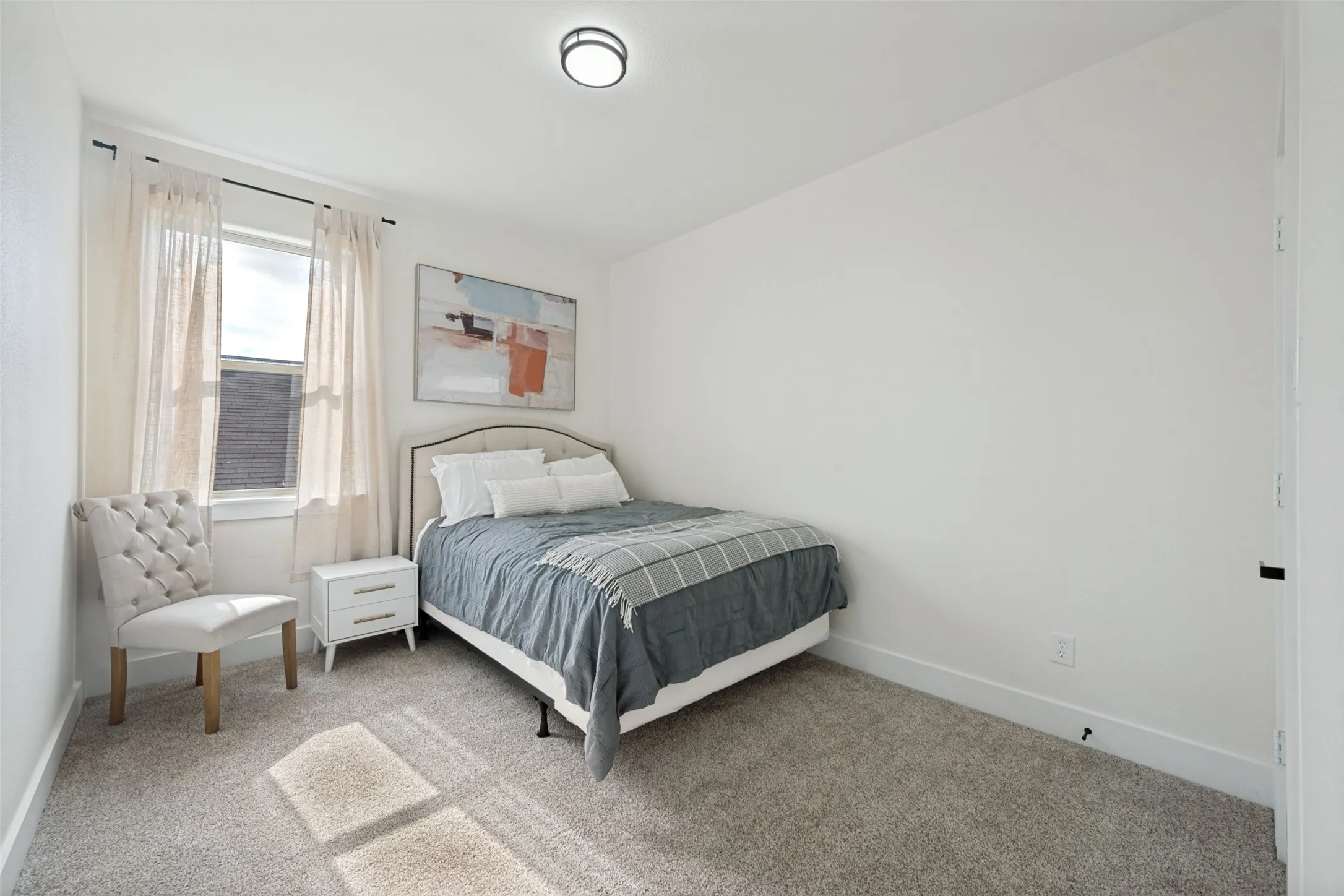 Bright interior space featuring a window, neutral carpet flooring, and a ceiling-mounted light fixture