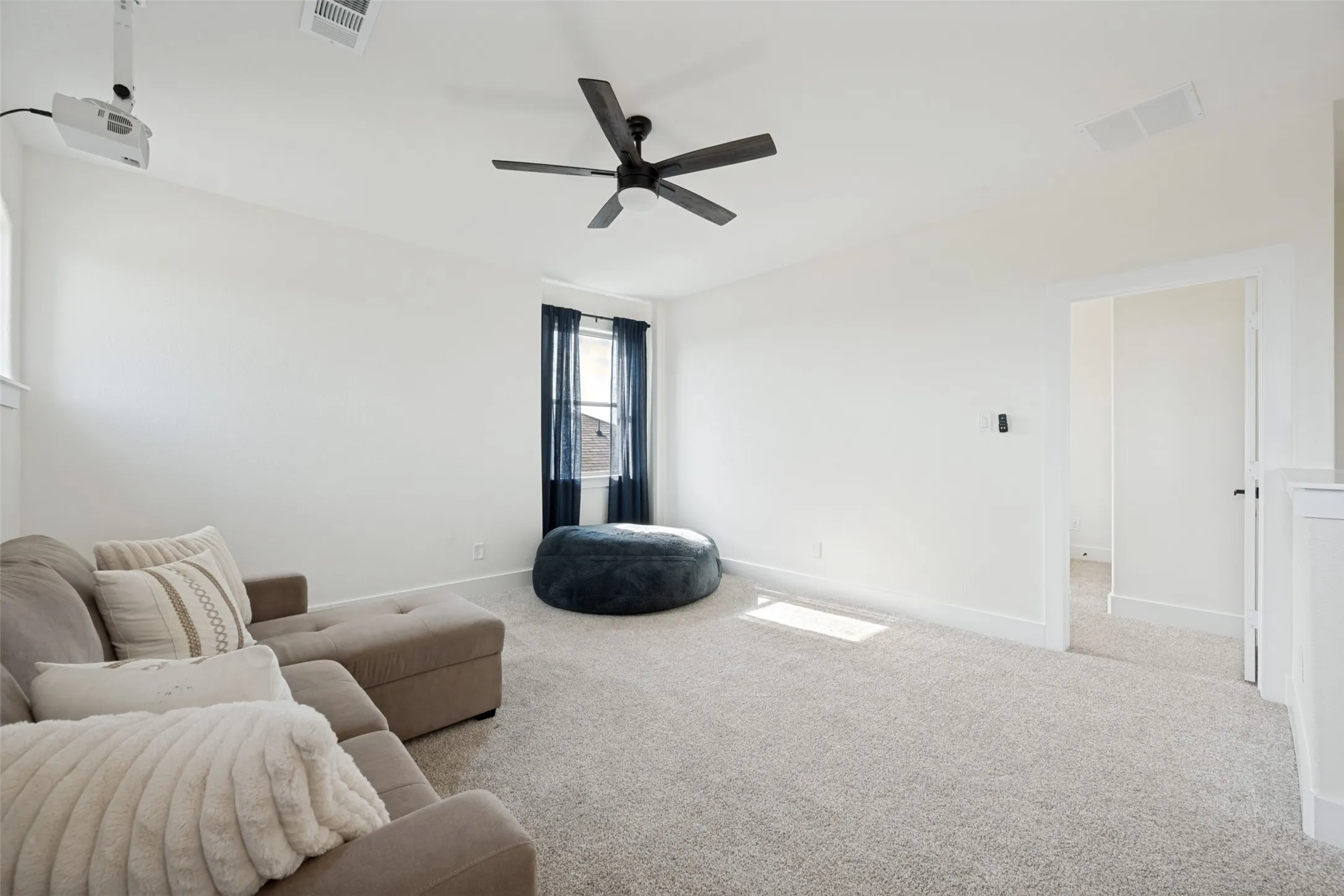 Spacious room featuring light-colored carpeting, a ceiling-mounted fan, and recessed lighting