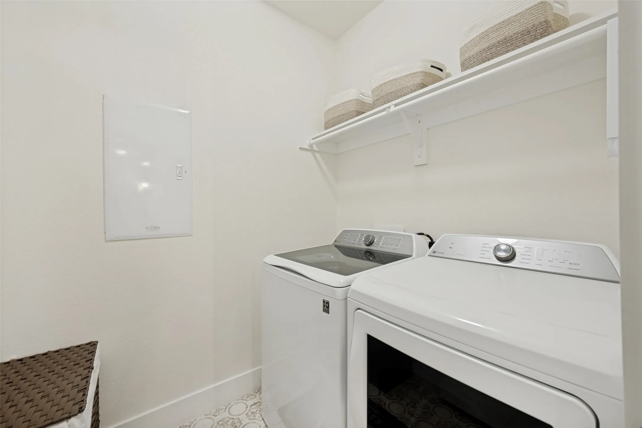 Dedicated utility space featuring patterned floor tile and a single white storage shelf