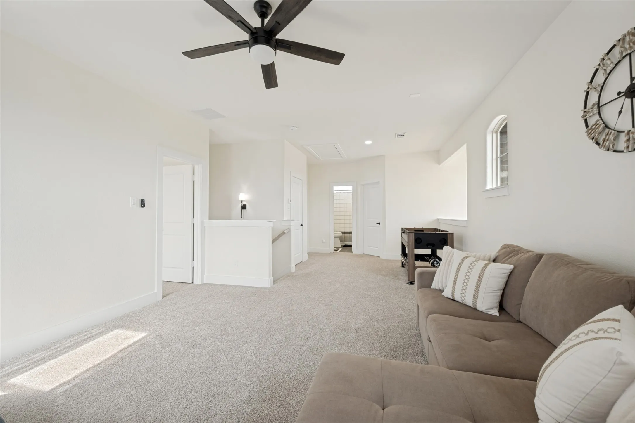Versatile bonus room featuring light-toned carpeting, a contemporary ceiling fan with dark blades, white trim, and a high arched window