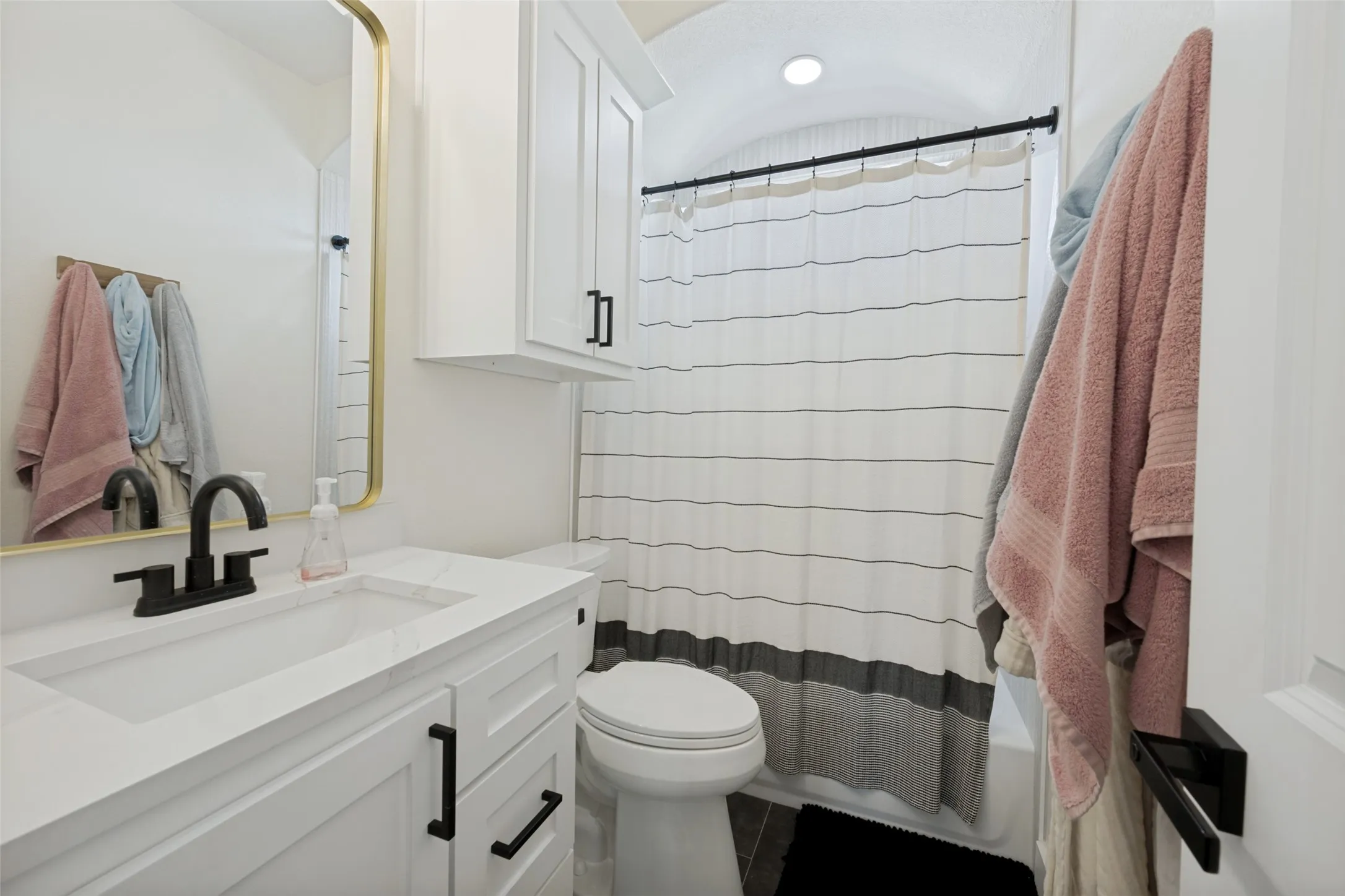 Bathroom featuring a white vanity with a rectangular basin, quartz-finish countertop, and matte black faucet