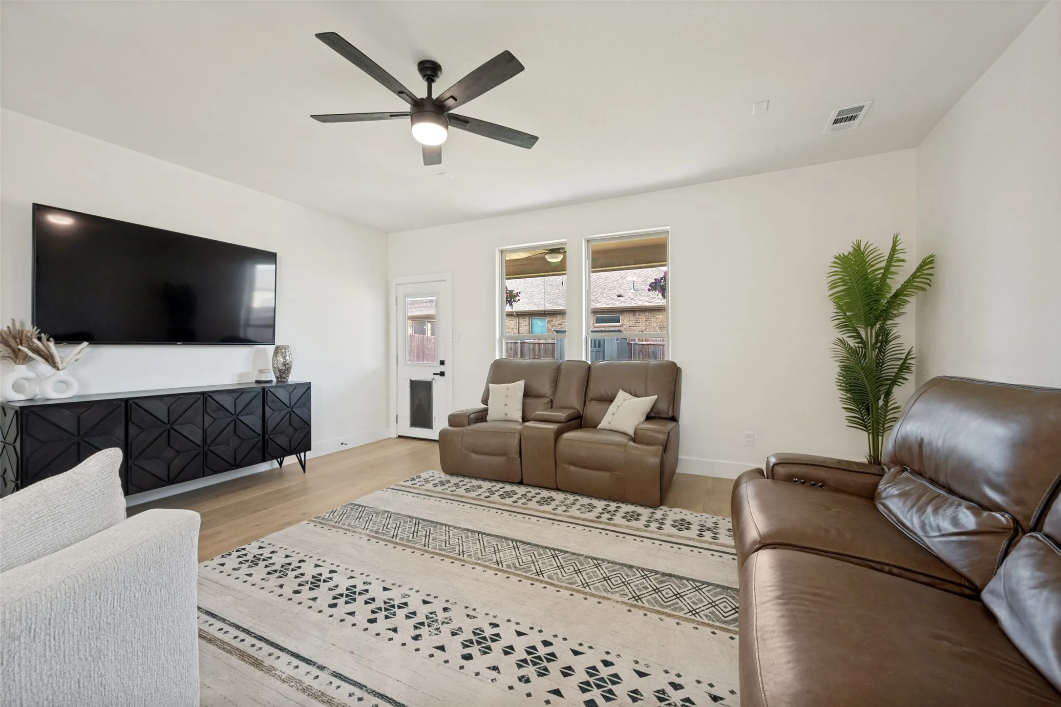 Bright living area featuring wood-finish flooring and a contemporary ceiling fan
