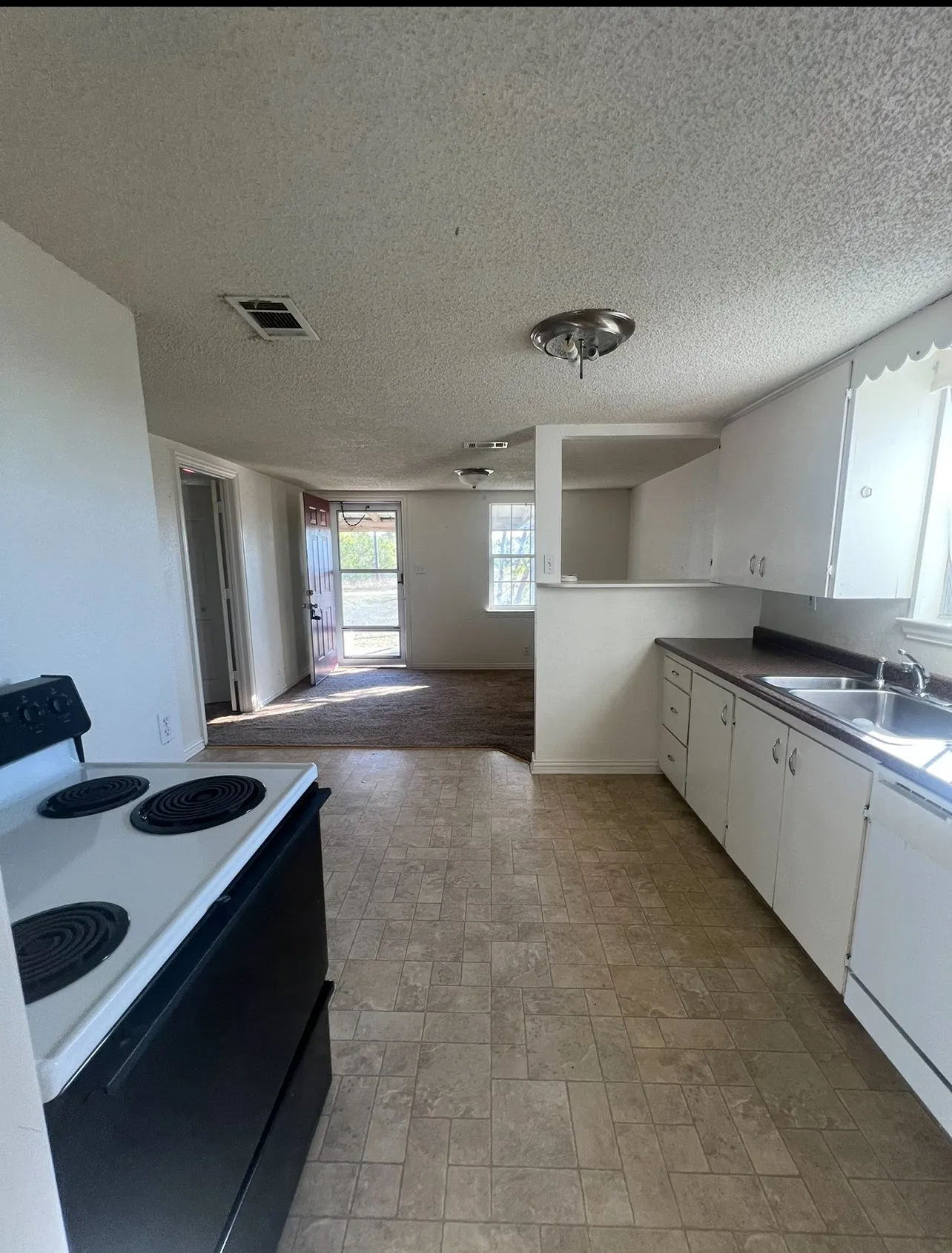 Functional kitchen featuring white cabinetry, a double basin stainless steel sink, and a black and white electric range