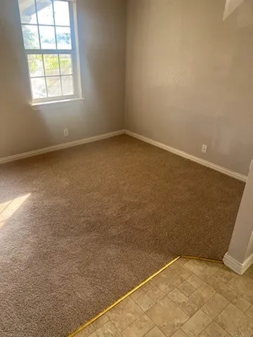 Room featuring neutral-toned walls, brown carpeting, and white baseboards