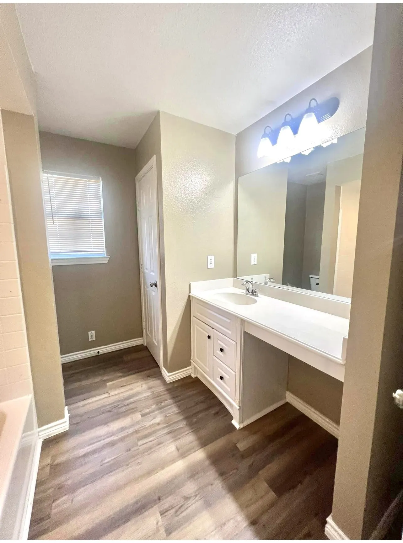 Vanity area featuring a built-in white cabinet, integrated sink, extended countertop, and wall-mounted light fixture