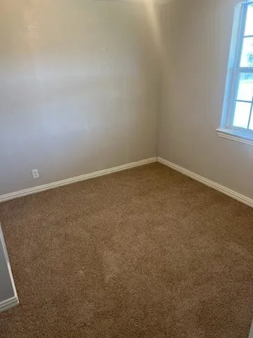 Light beige walls complement the brown carpet flooring and white baseboards