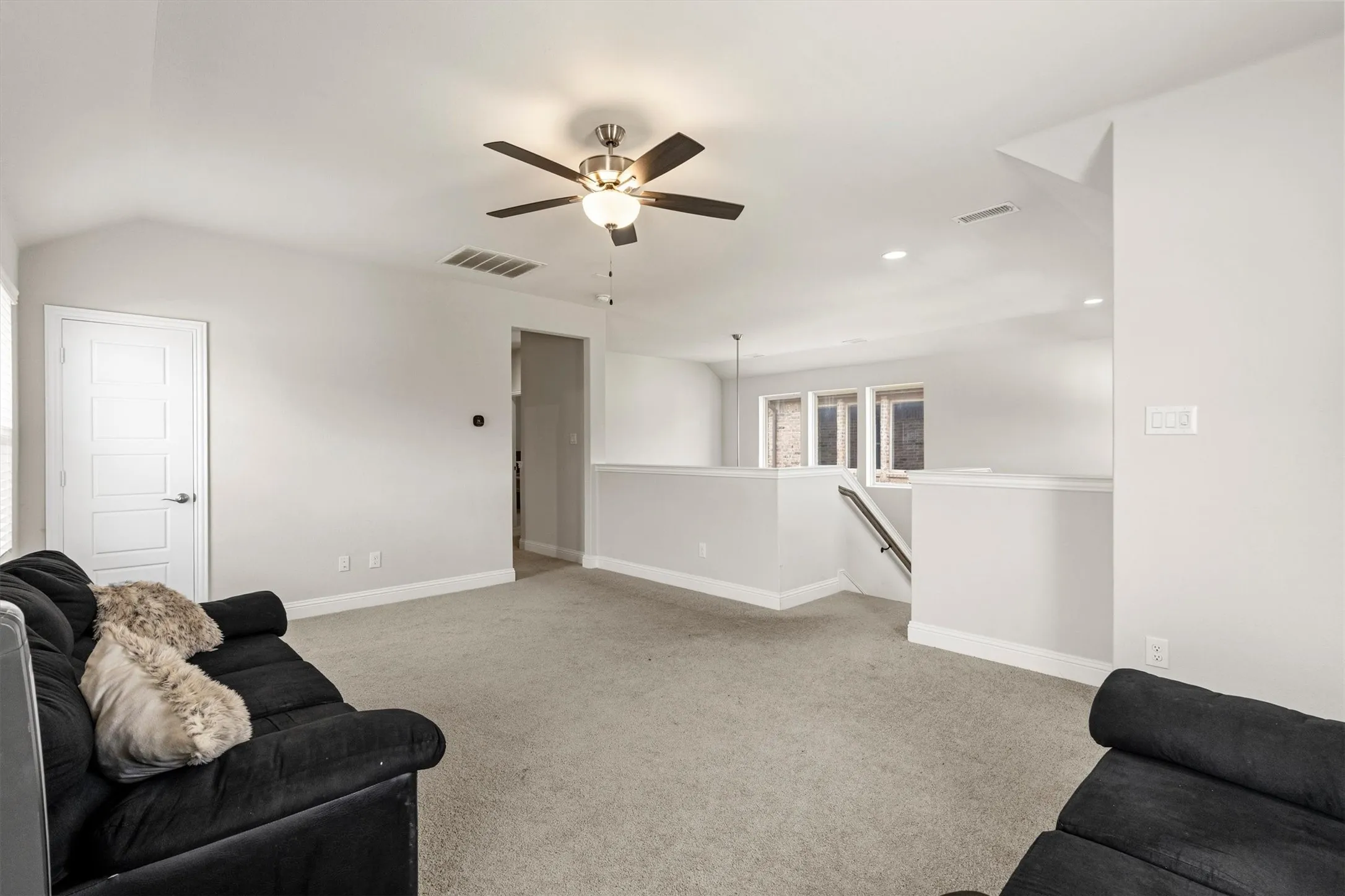 Spacious carpeted upper-level landing featuring a contemporary ceiling fan with integrated lighting, recessed lighting, and a white paneled door
