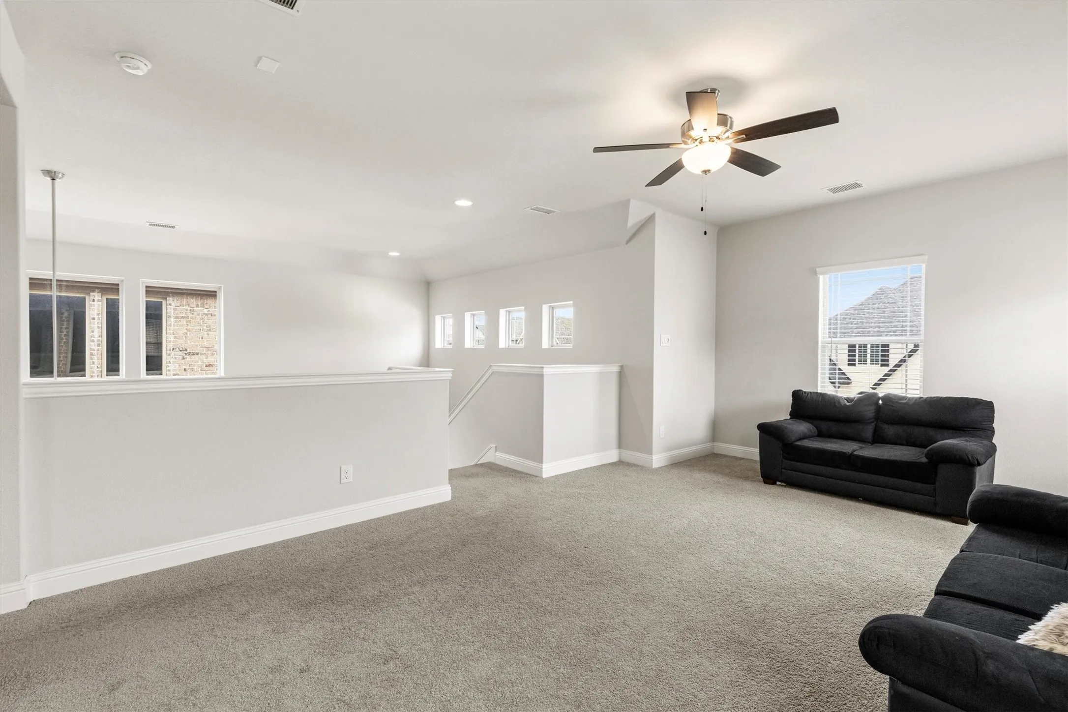 Spacious loft area featuring neutral carpeting and light gray walls