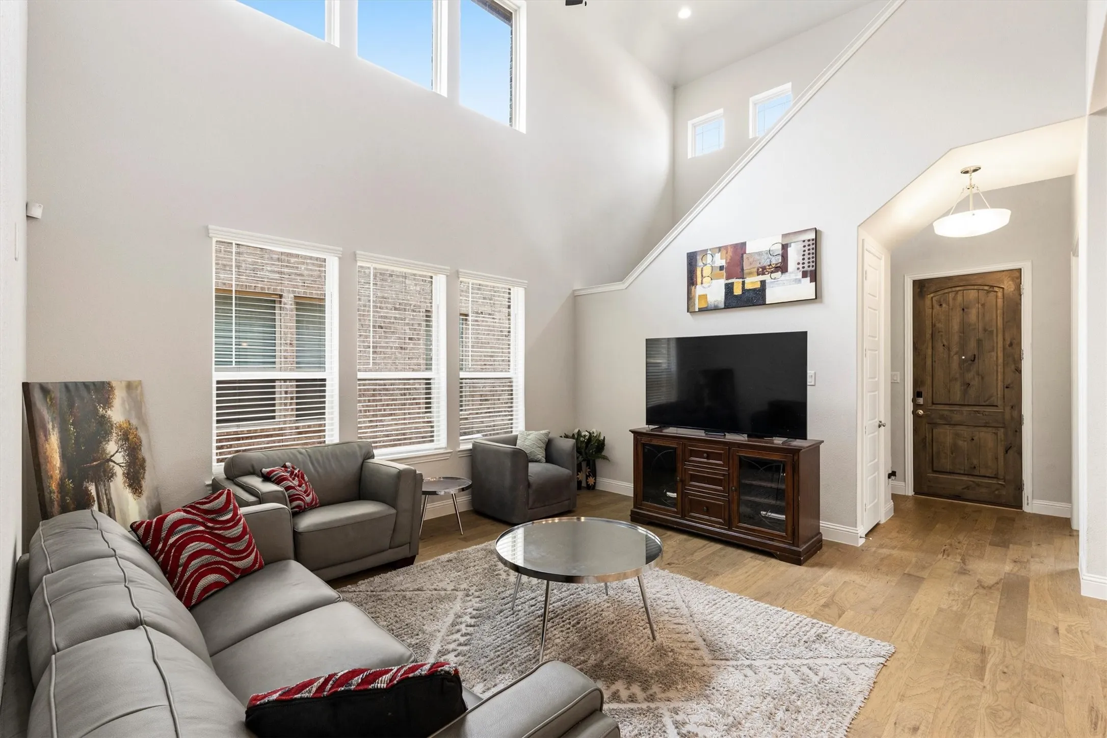 Spacious living area featuring high ceilings, upper-story windows, and wood-finish flooring