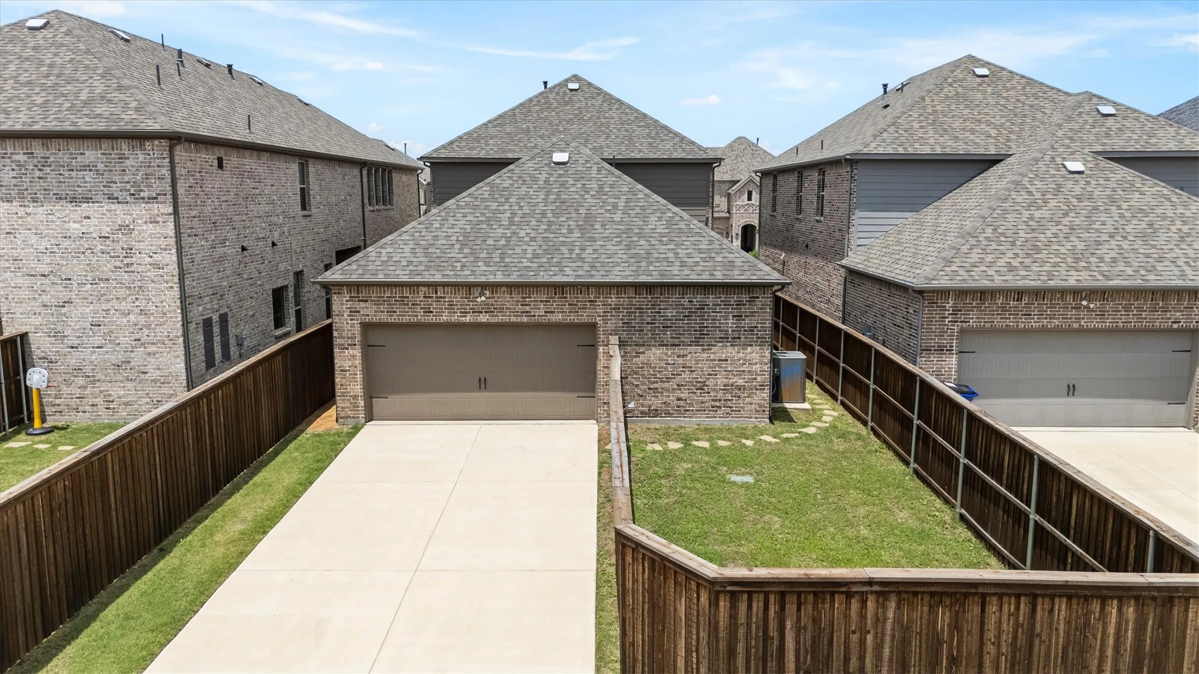 Attached garage with a paved driveway, brick exterior, and shingle roof