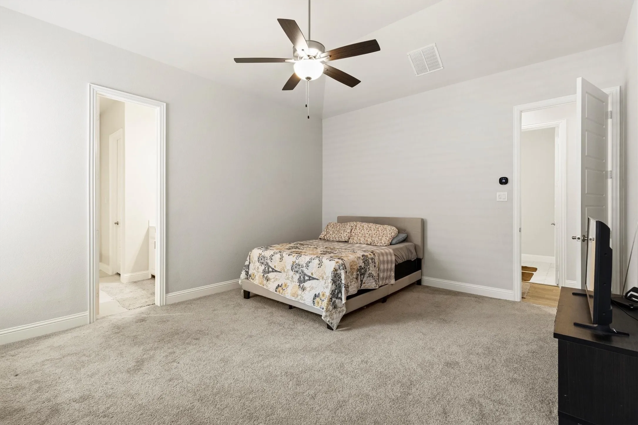 Spacious room featuring light gray walls, plush gray carpeting, and white trim