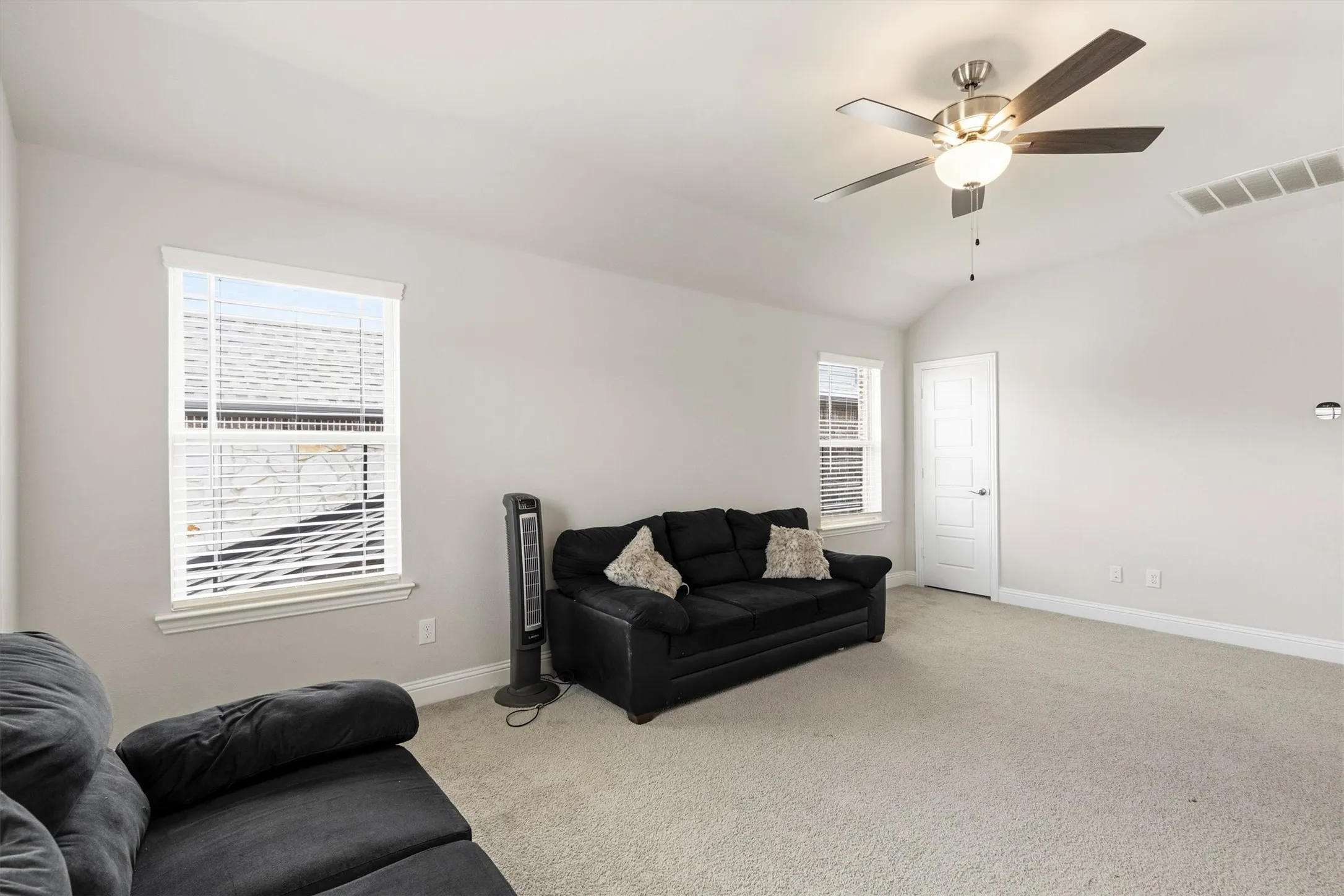 Spacious room featuring vaulted ceilings, neutral-toned walls, and plush carpeting