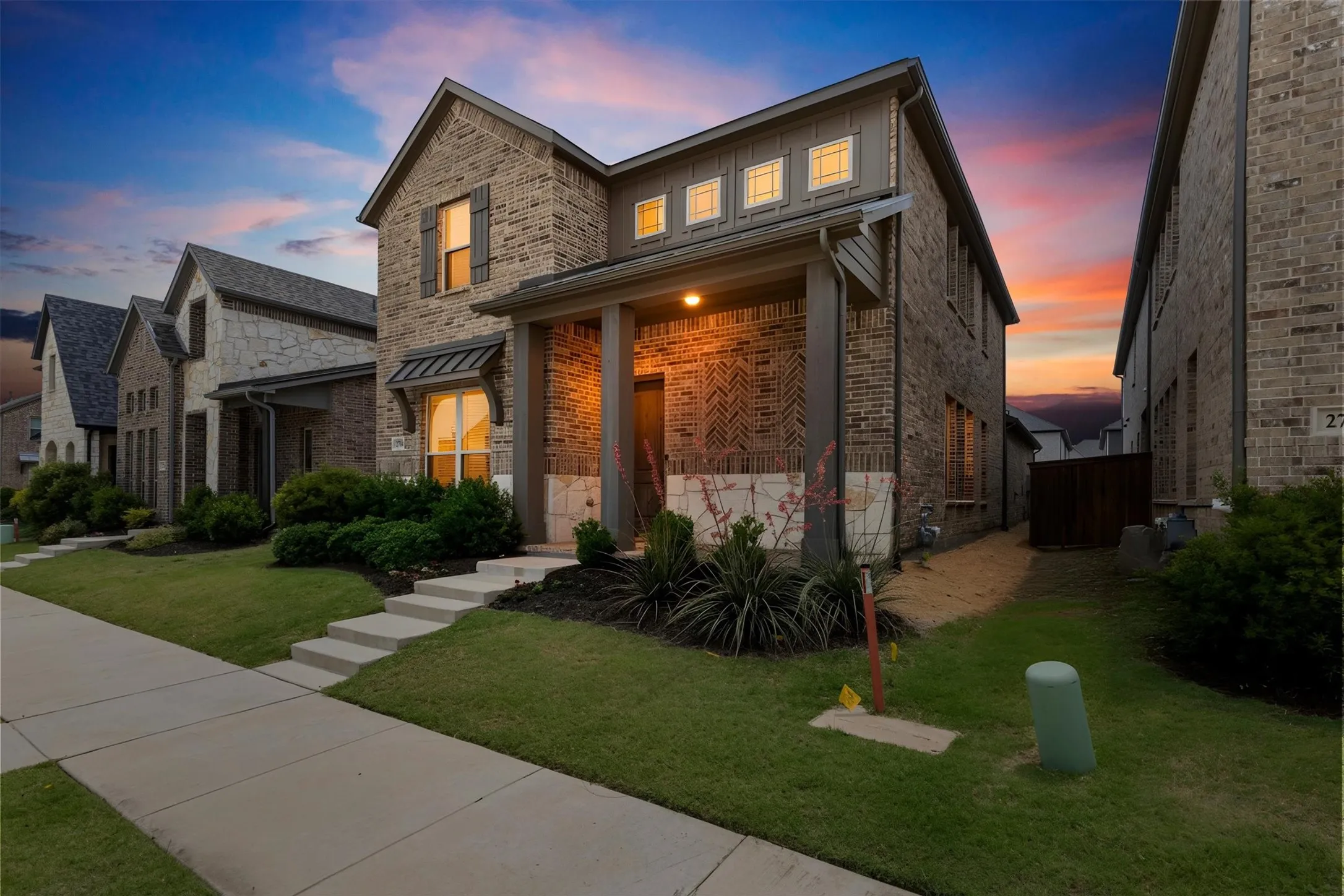 Brick facade home featuring a covered front porch, decorative shutters, and a manicured lawn