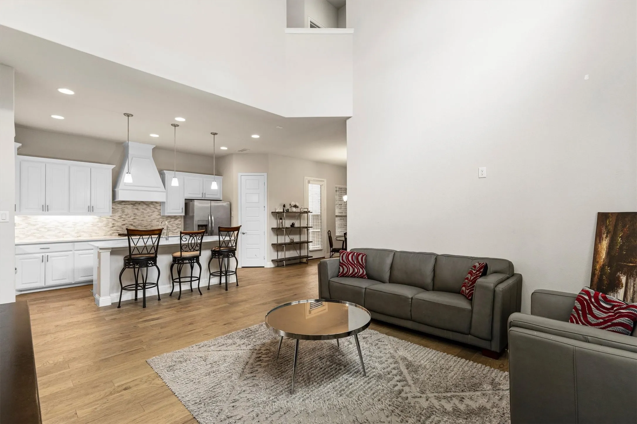 Open-concept living space featuring wood-finish flooring, a two-story ceiling, and recessed lighting