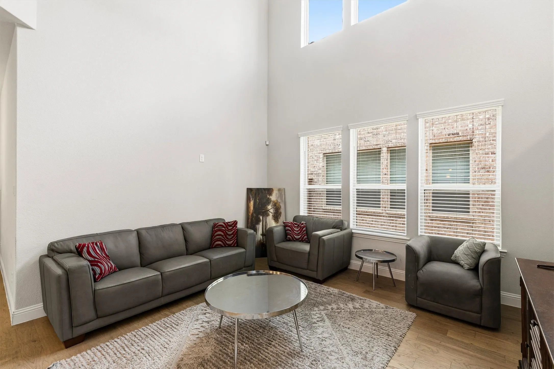 Soaring two-story ceilings with upper windows and three lower windows featuring blinds