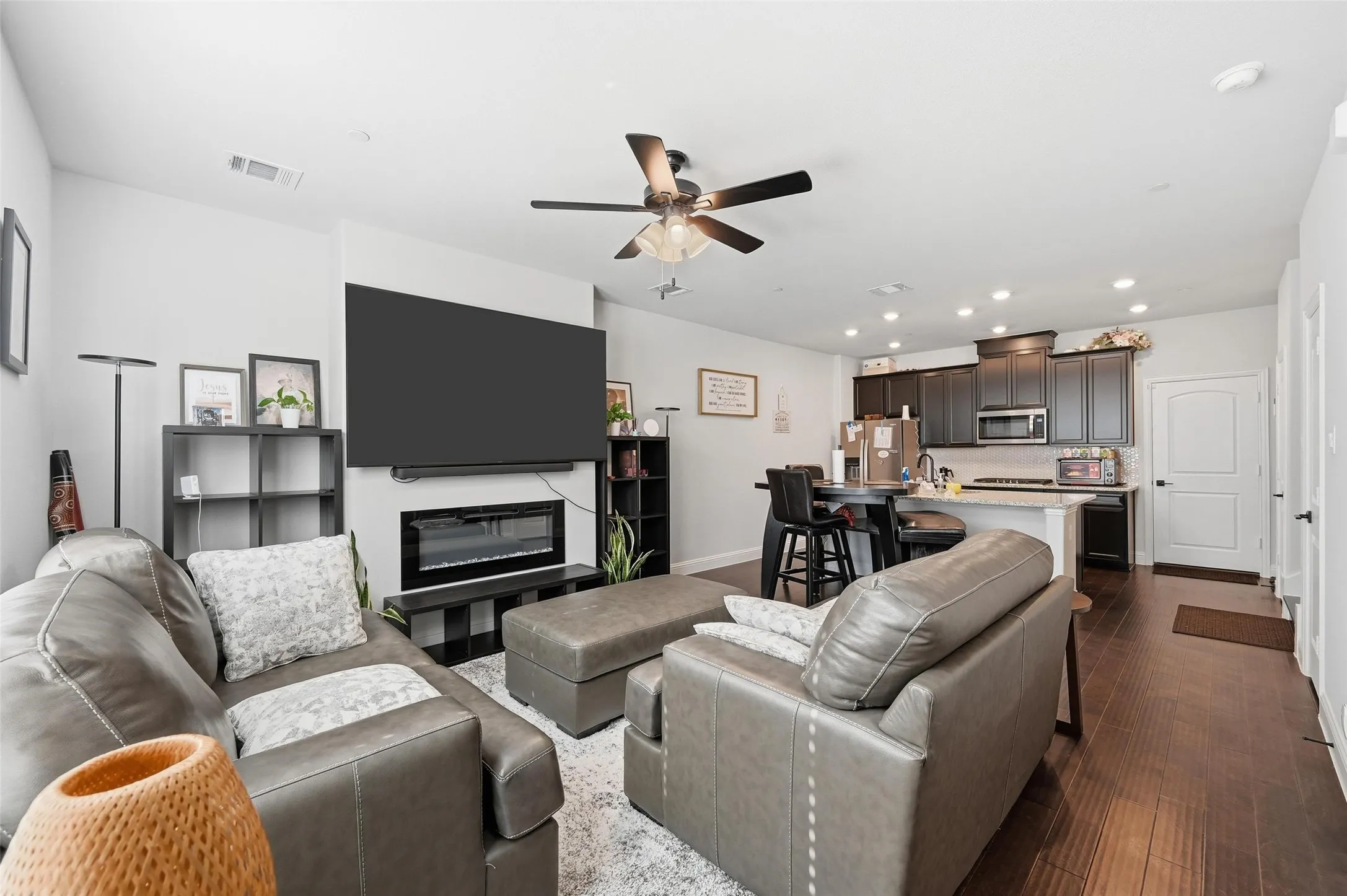 Living room with dark wood-style floors, recessed lighting, a glass covered fireplace, and ceiling fan