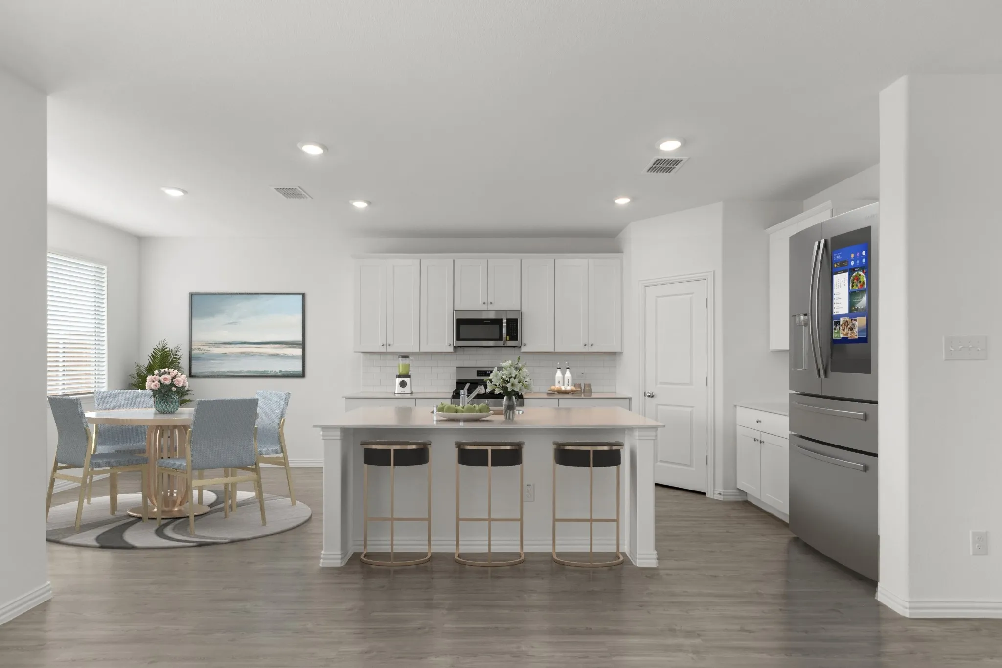 Open-concept kitchen and dining area featuring a central island with seating, stainless steel appliances, white cabinetry, and wood-finish flooring