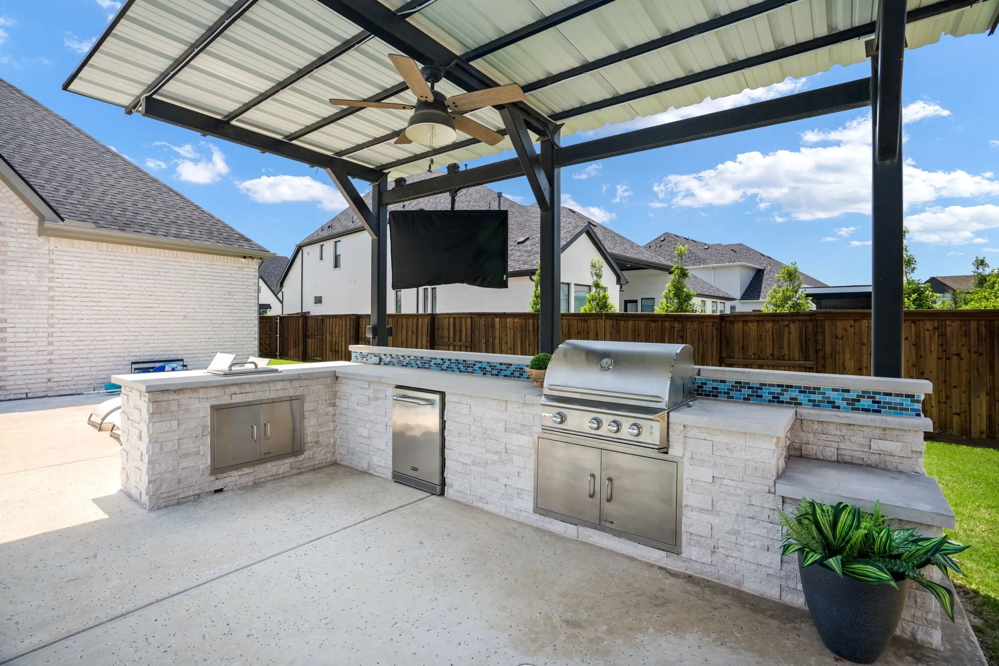 Outdoor kitchen with grill, fridge and tv