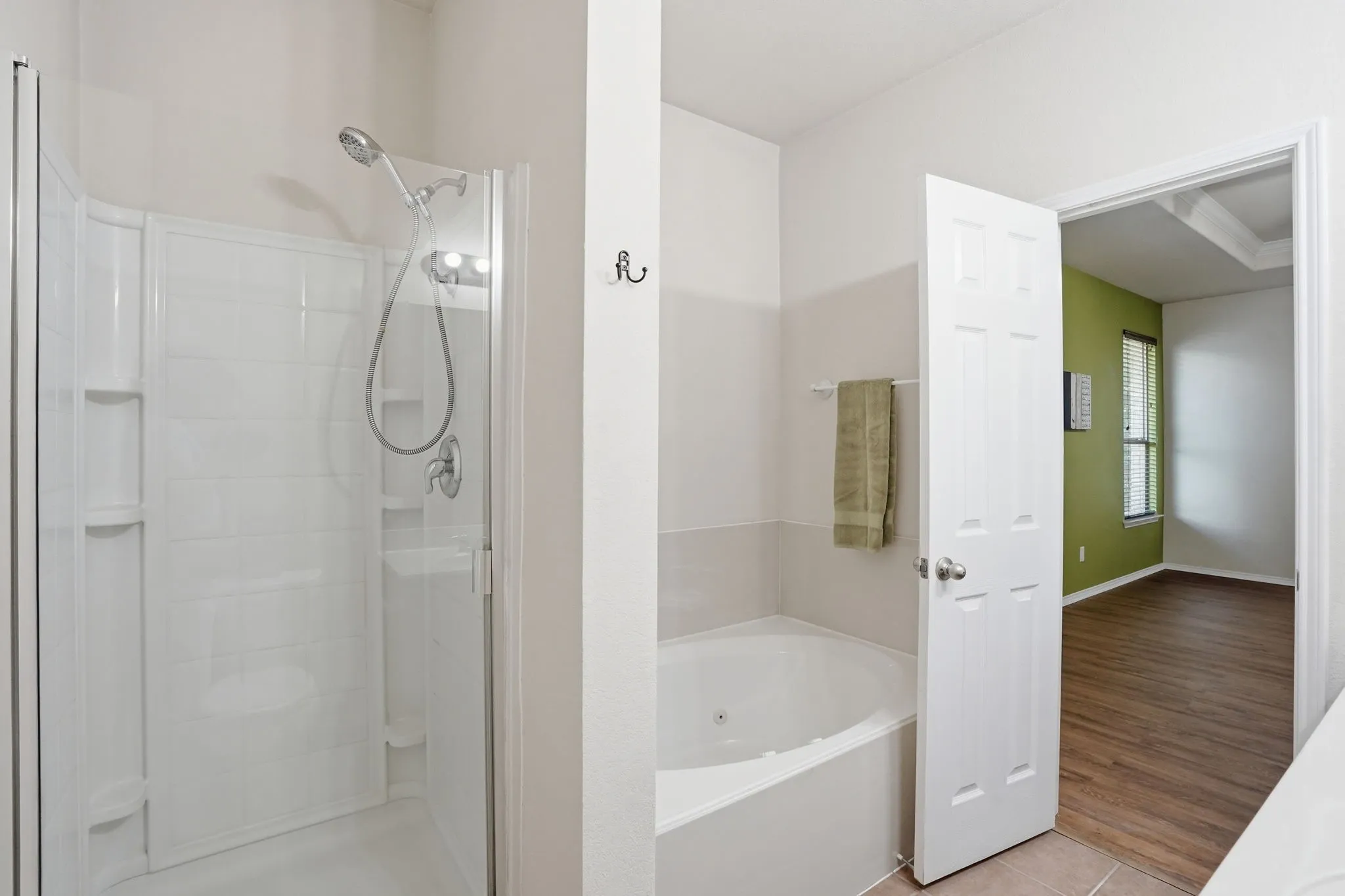 Bathroom featuring a glass-enclosed shower with a handheld spray fixture, a separate soaking tub, and tiled flooring